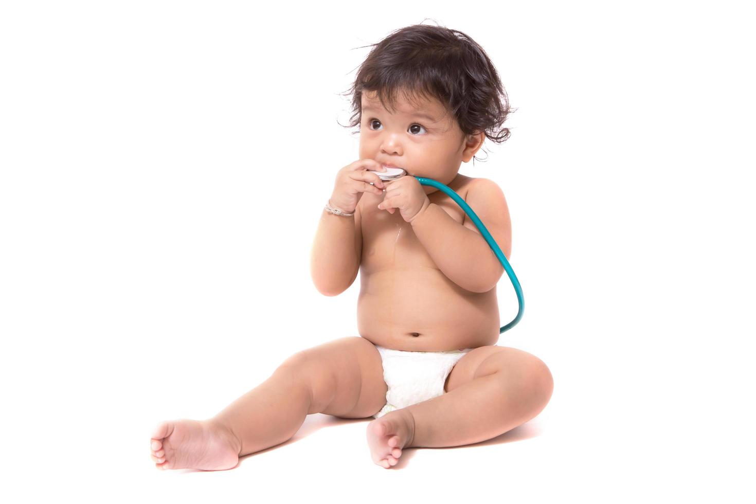 Little baby sitting on floor wearing and holding a stethoscope photo