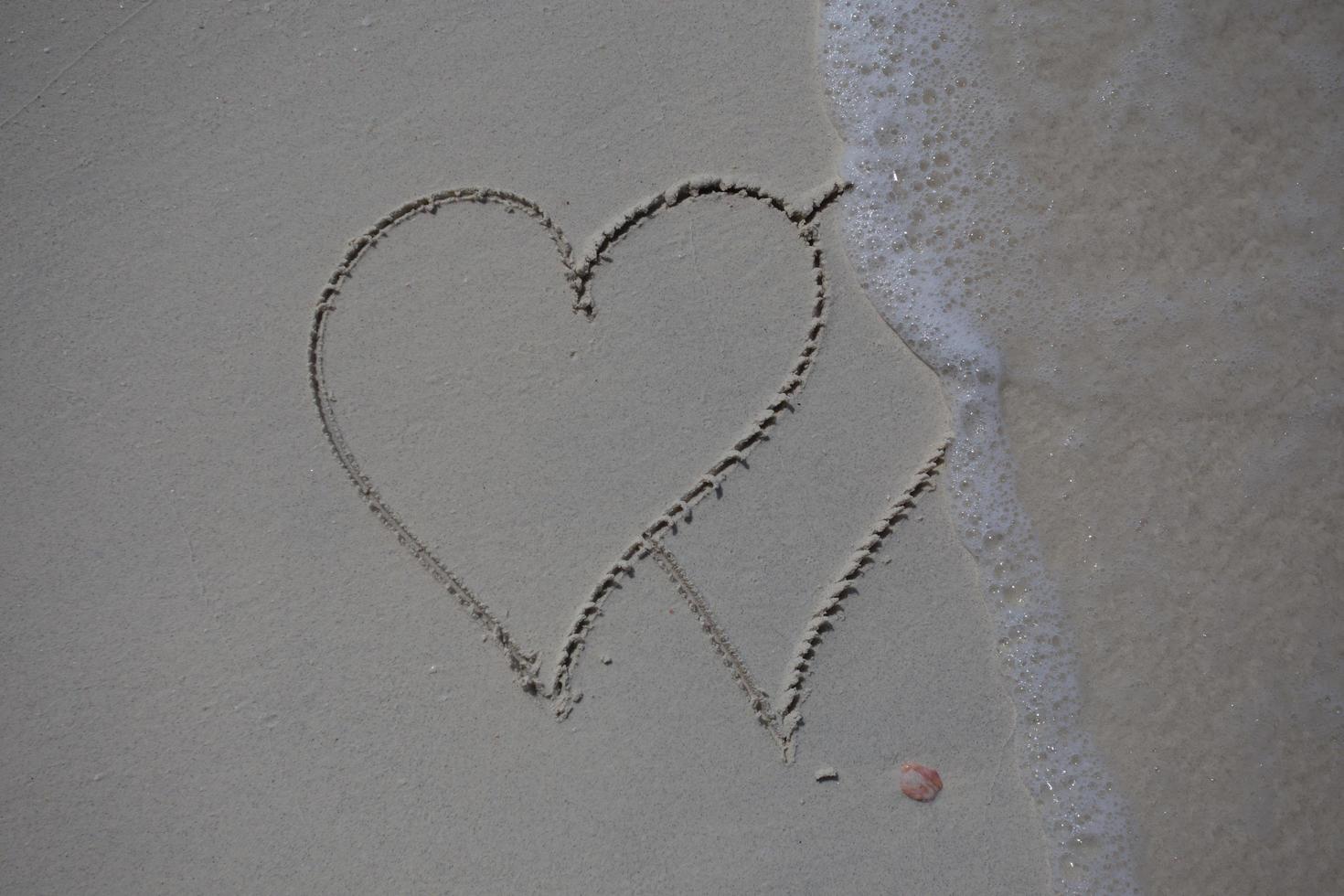 corazones dibujados en la arena de una playa foto