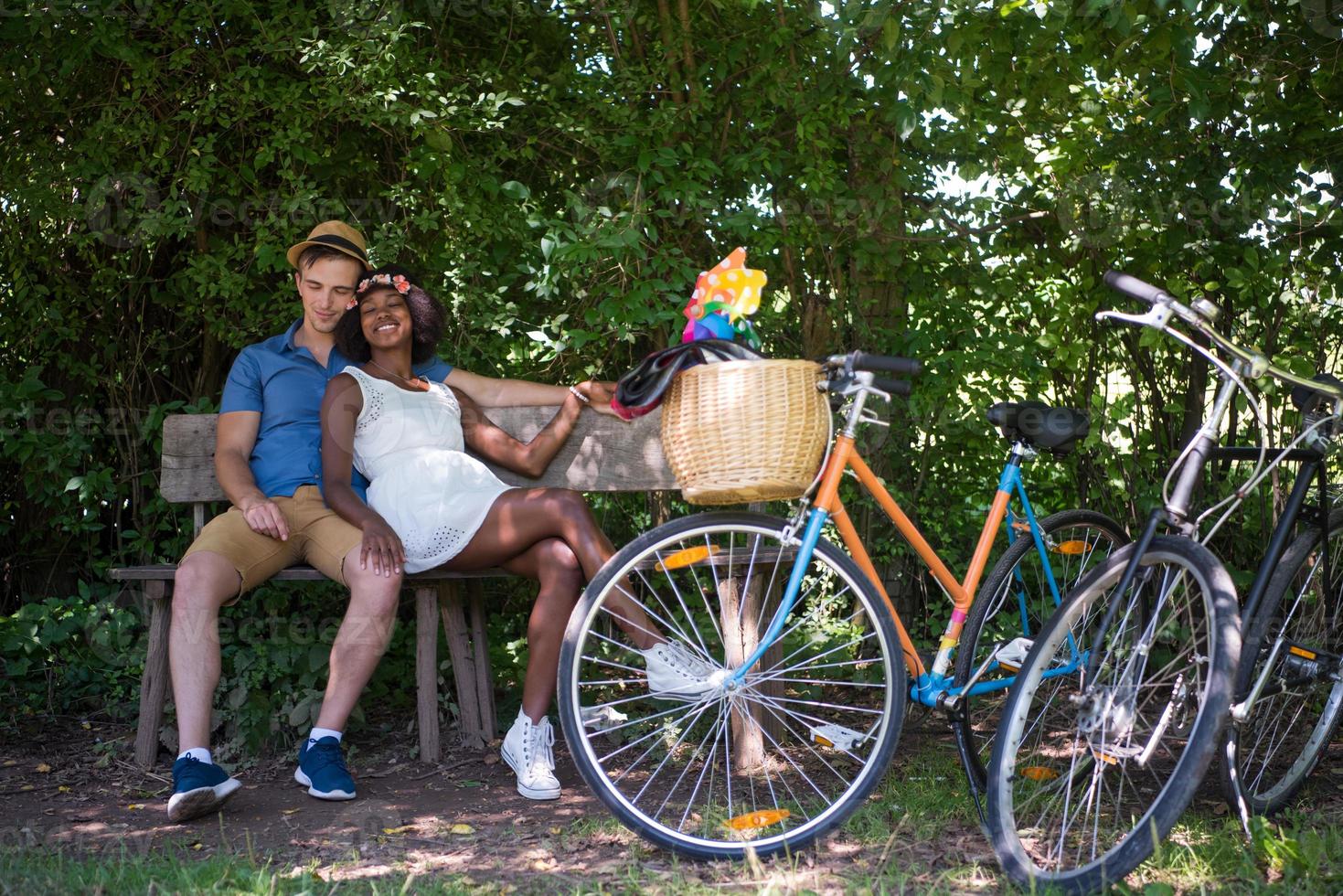 joven pareja multiétnica dando un paseo en bicicleta en la naturaleza foto