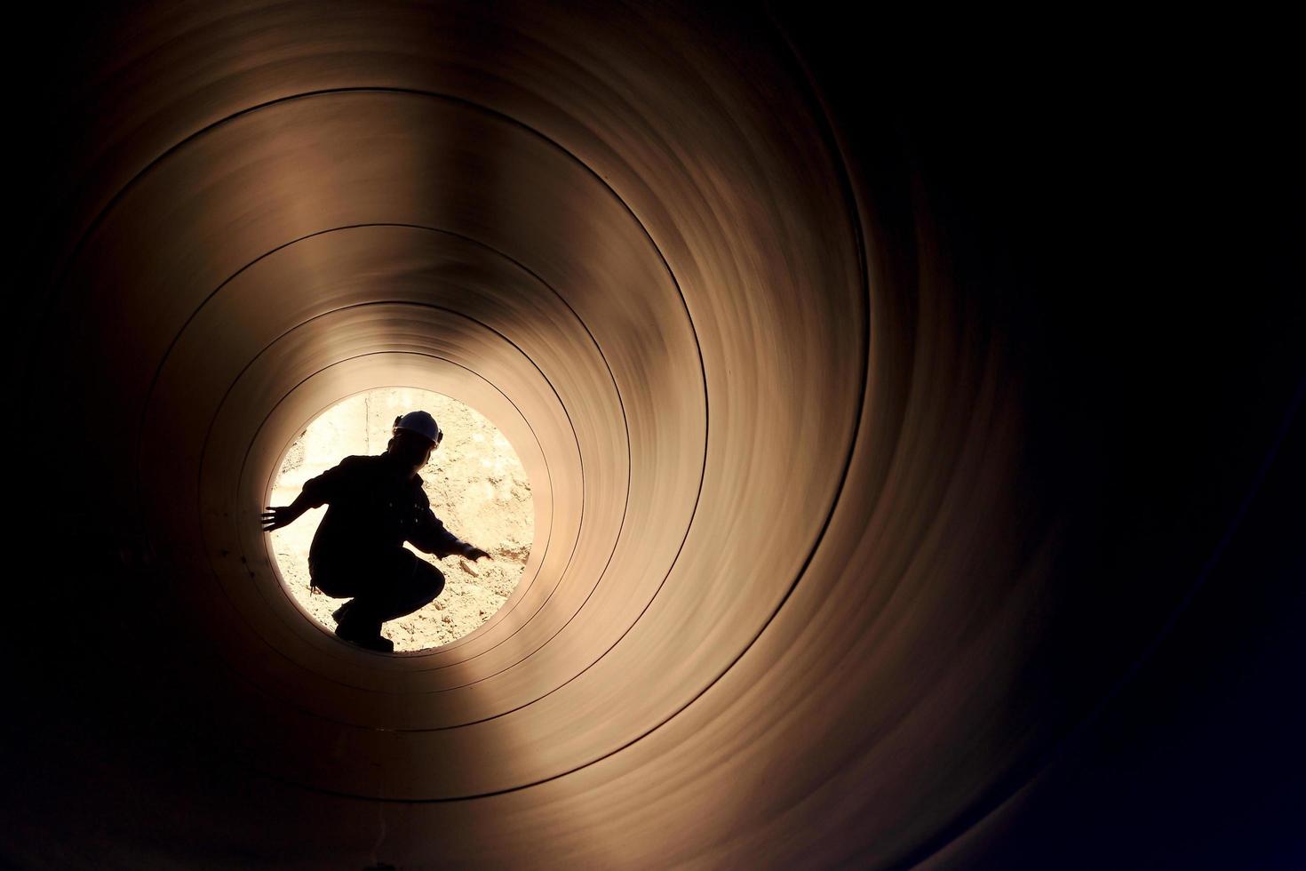 A silhouette of a worker in pipe photo