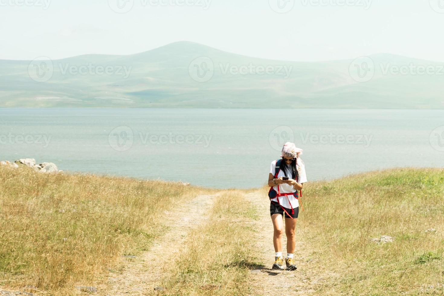 Woman use phone navigation outdoors to navigate on hiking trail to reach destination in caucasus mountains photo