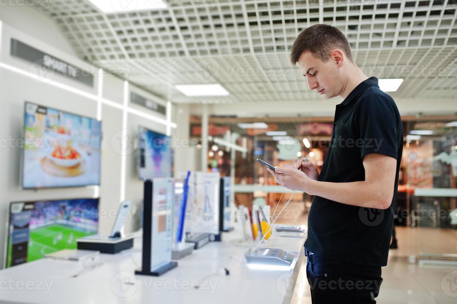 Seller man mobile phone professional consultant in tech store or shop hold new smartphone at  hand. photo