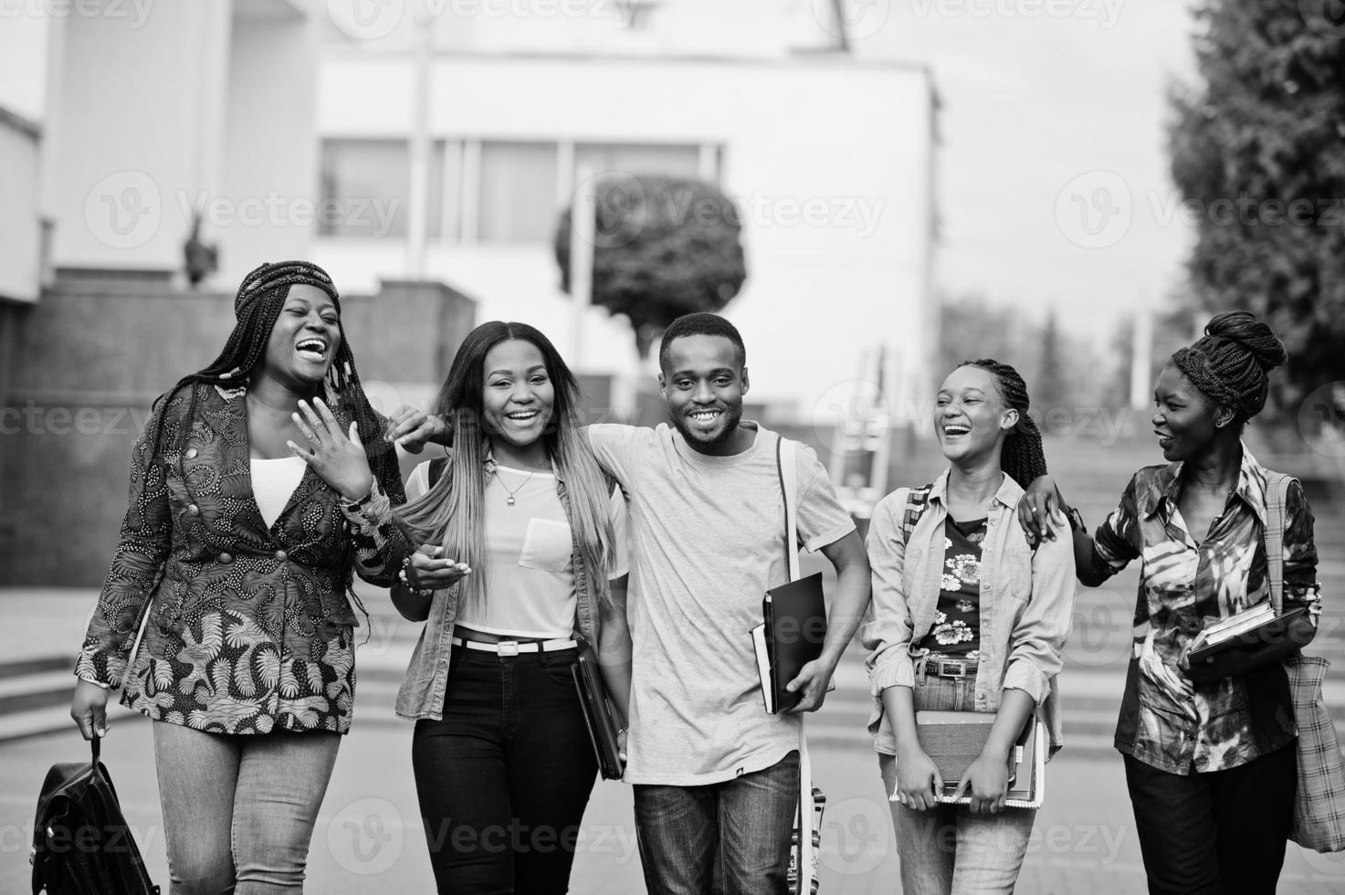 grupo de cinco estudiantes universitarios africanos que pasan tiempo juntos en el campus en el patio de la universidad. amigos negros afro estudiando. tema de la educación foto