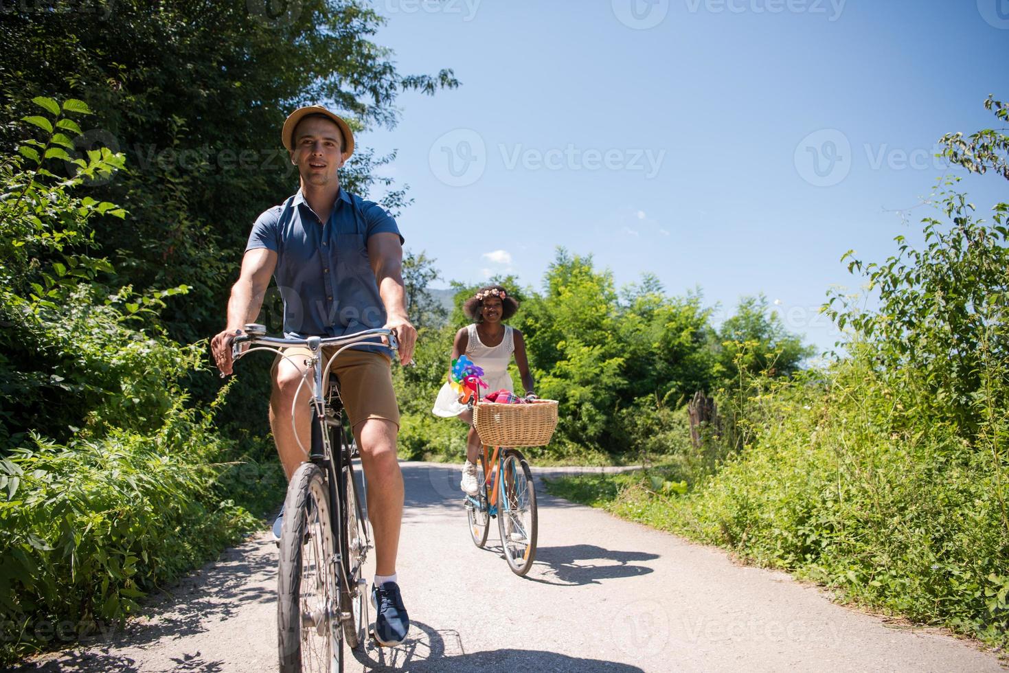 joven pareja multiétnica dando un paseo en bicicleta en la naturaleza foto