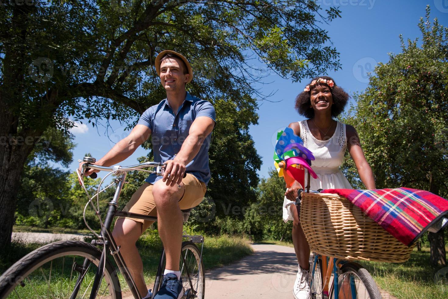 joven pareja multiétnica dando un paseo en bicicleta en la naturaleza foto