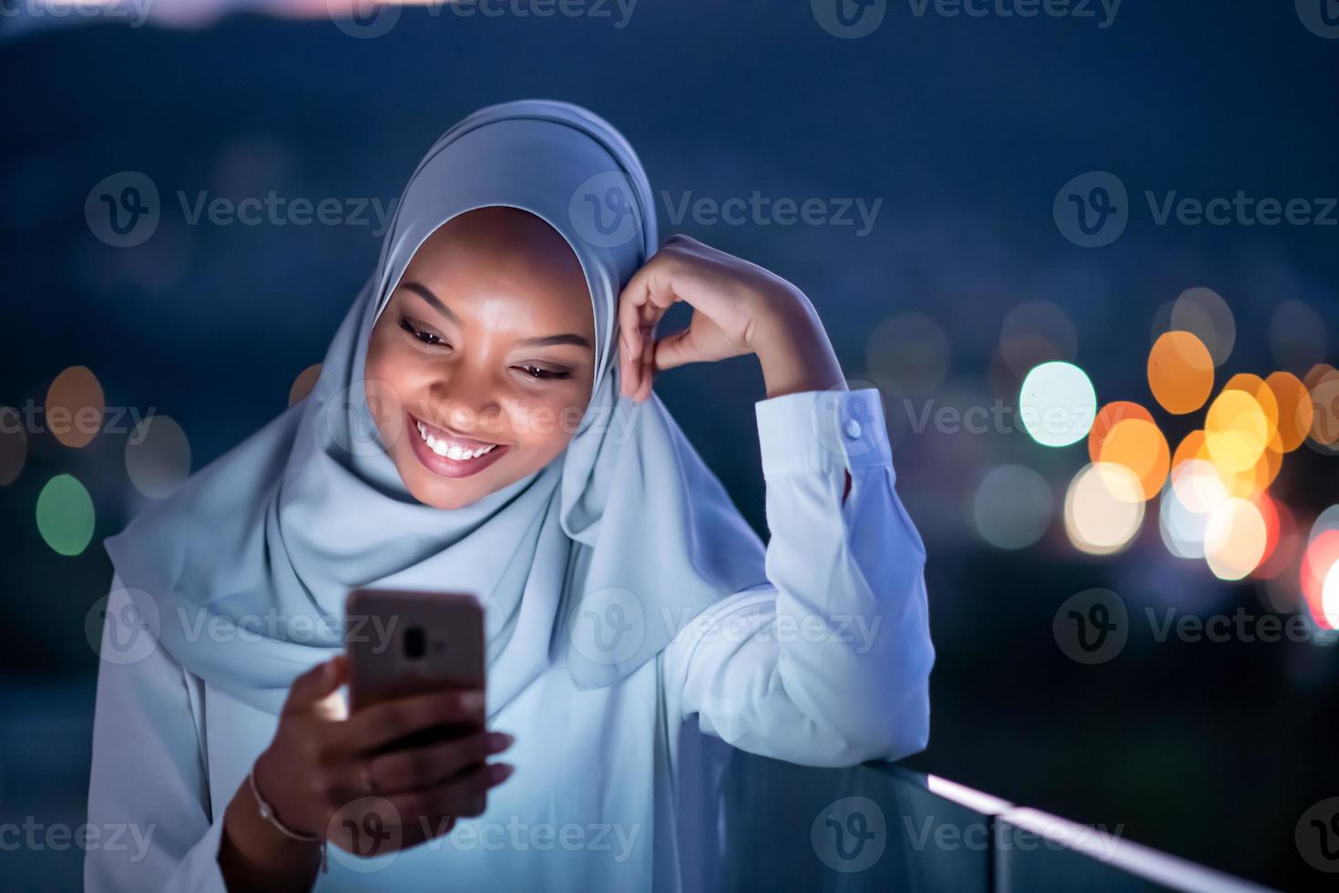 joven musulmana en la calle por la noche usando el teléfono foto