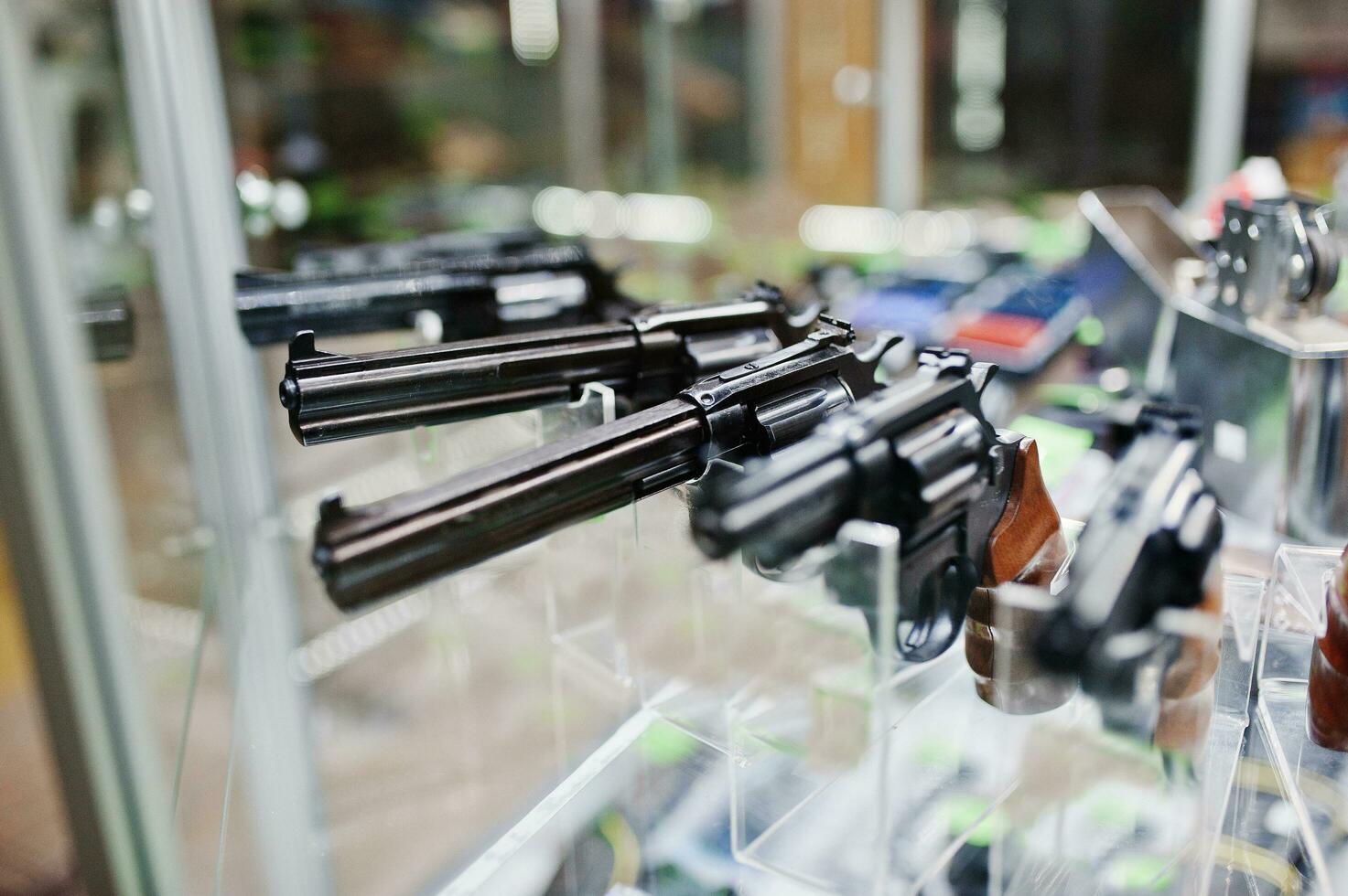 Different guns and revolvers on shelves store weapons on shop center. photo