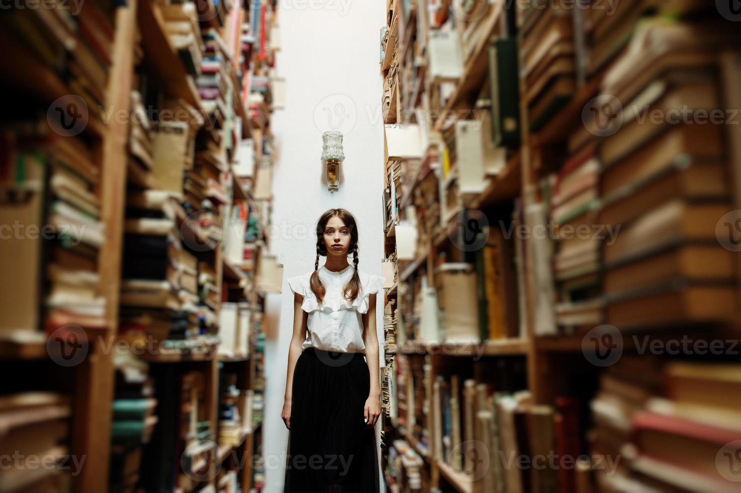 chica con coletas en blusa blanca en la antigua biblioteca. foto