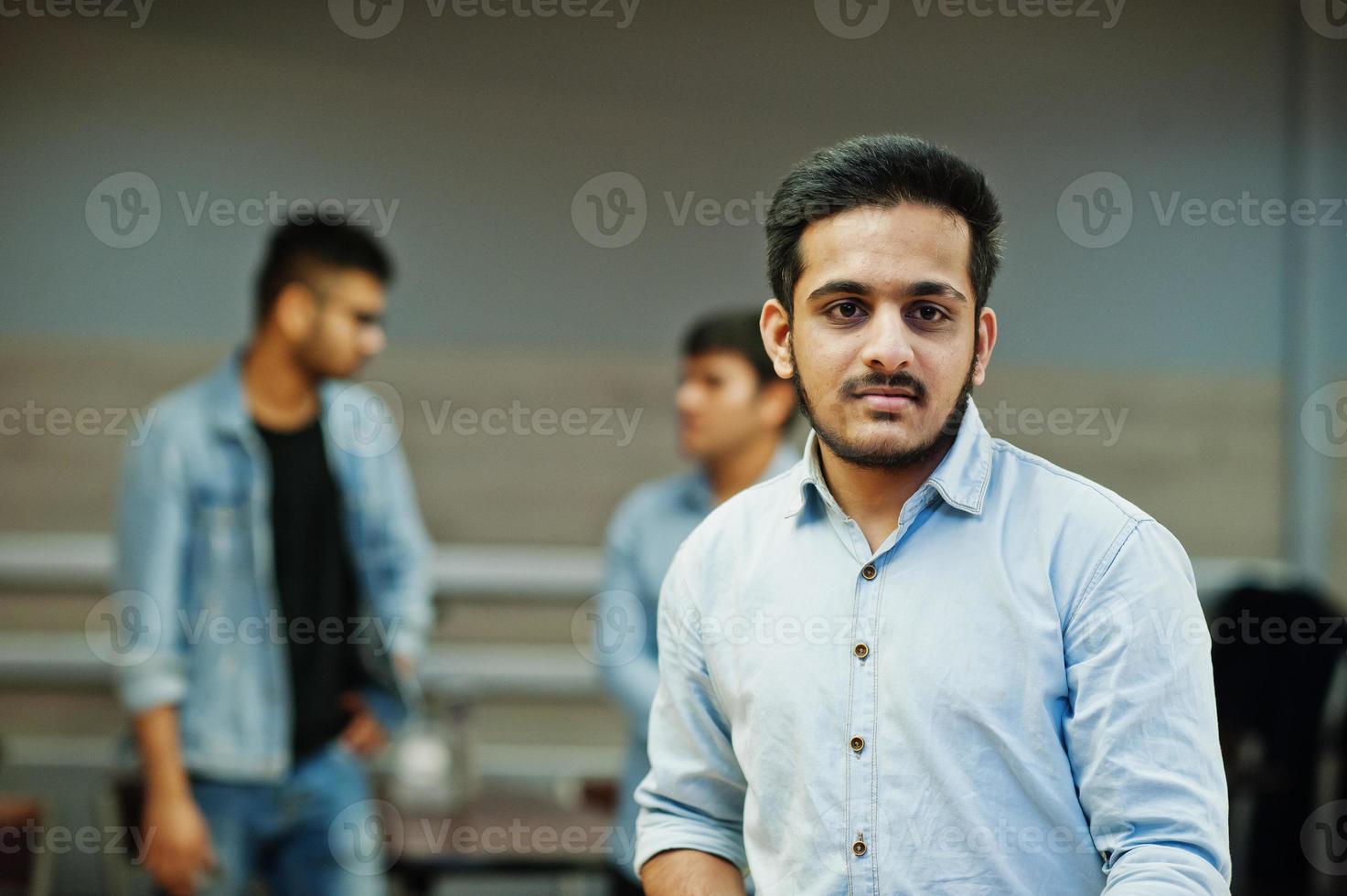 South asian man in jeans shirt standing at bowling alley with ball on hands. Guy is preparing for a throw. photo