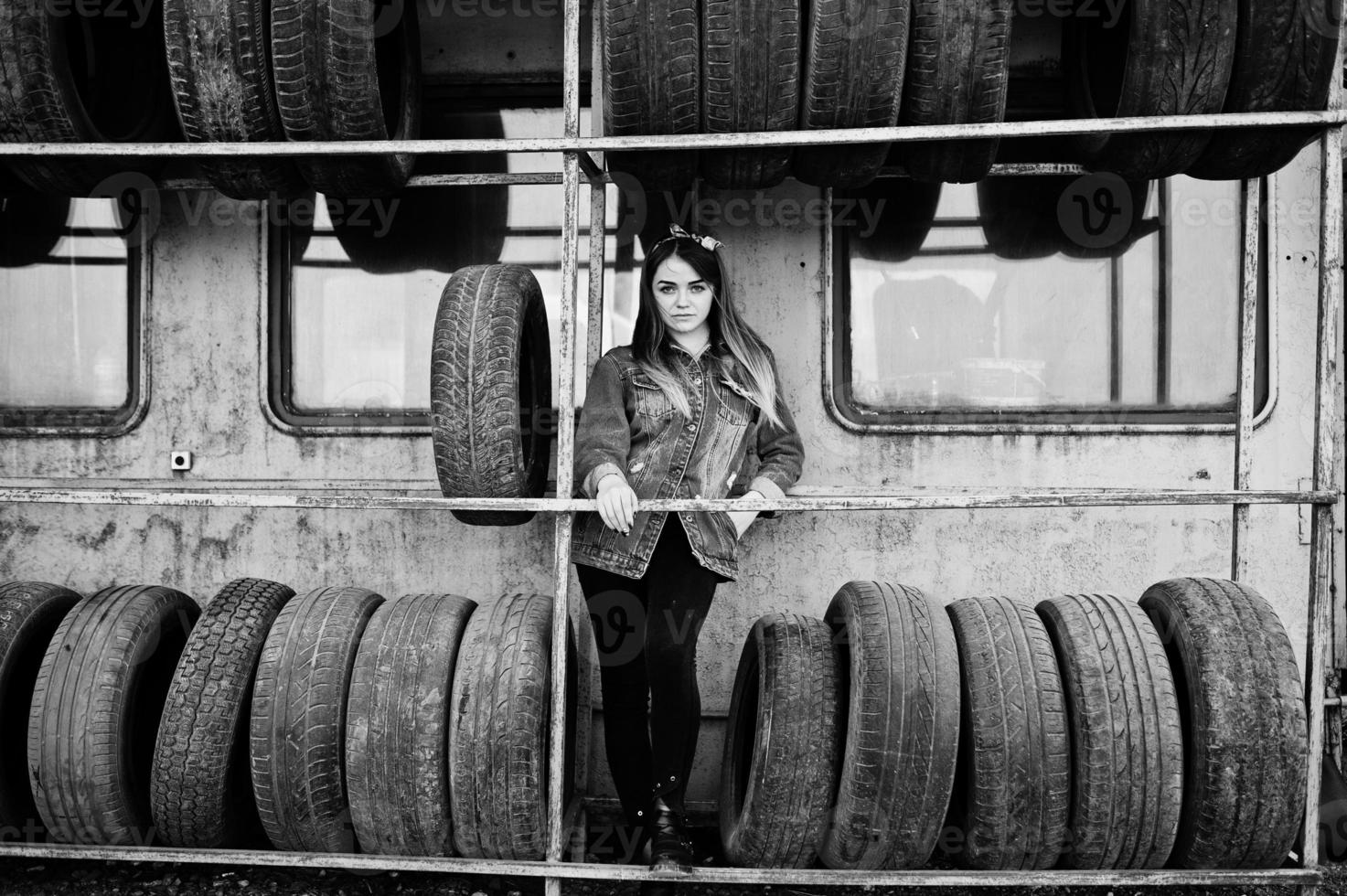 Young hipster girl in jeans jacket and head scarf at tire fitting zone. photo