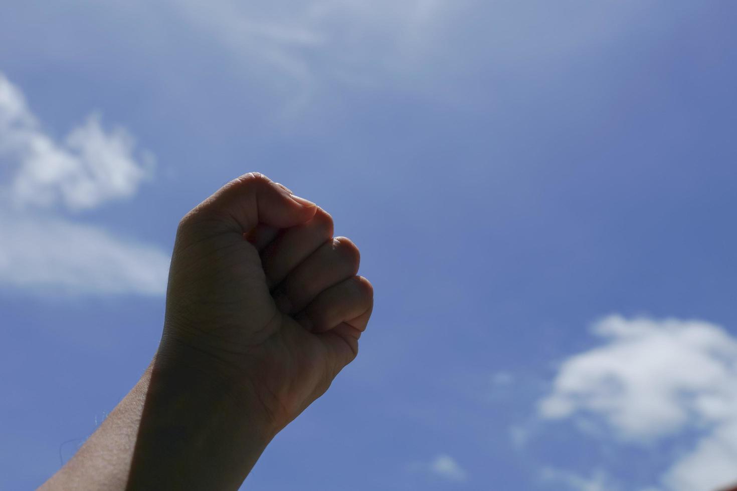 mano izquierda sostenida sobre un fondo celeste foto