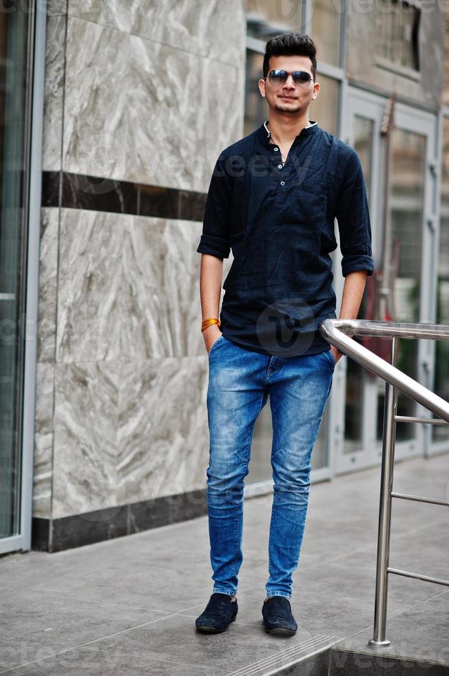 Stylish indian model man in casual clothes and sunglasses posed outdoor at street of India. photo