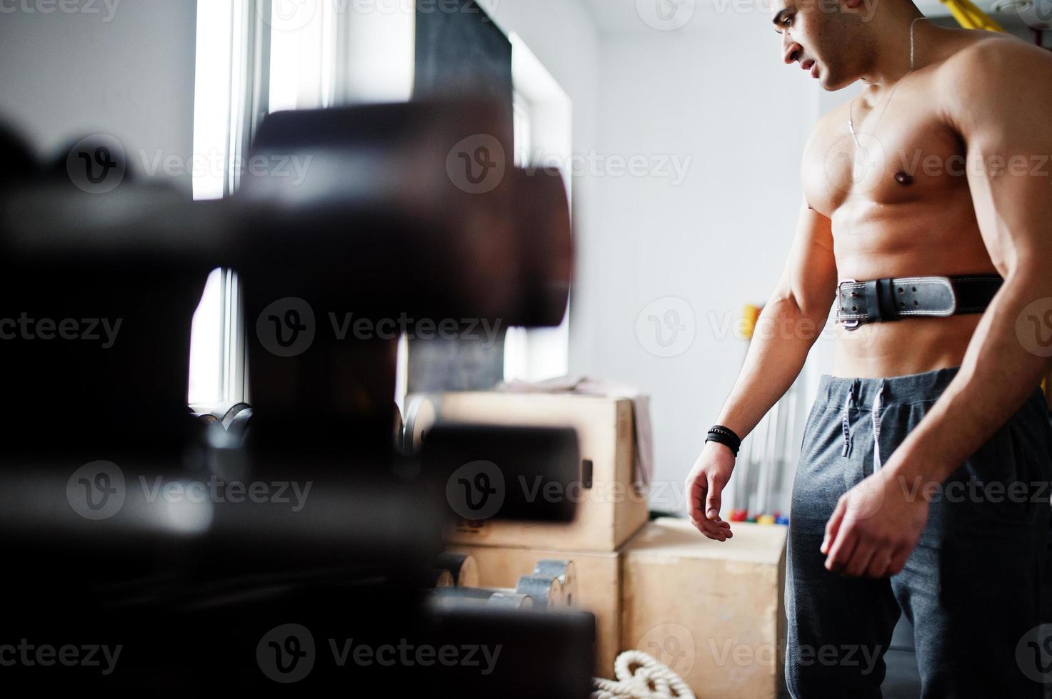 Fit and muscular arabian man doing workouts in gym. photo