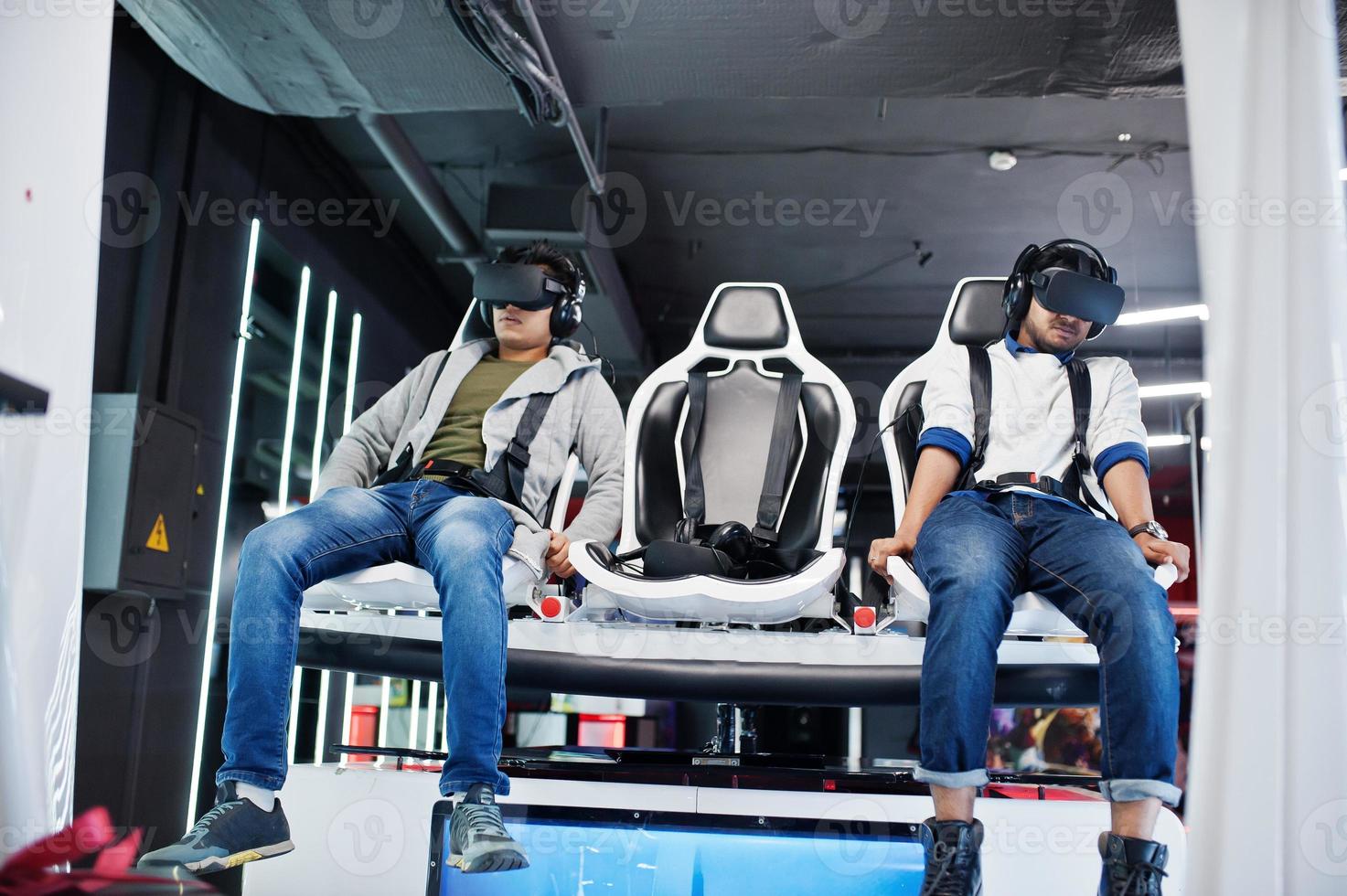 Two young indian people having fun with a new technology of a vr headset at virtual reality simulator. photo