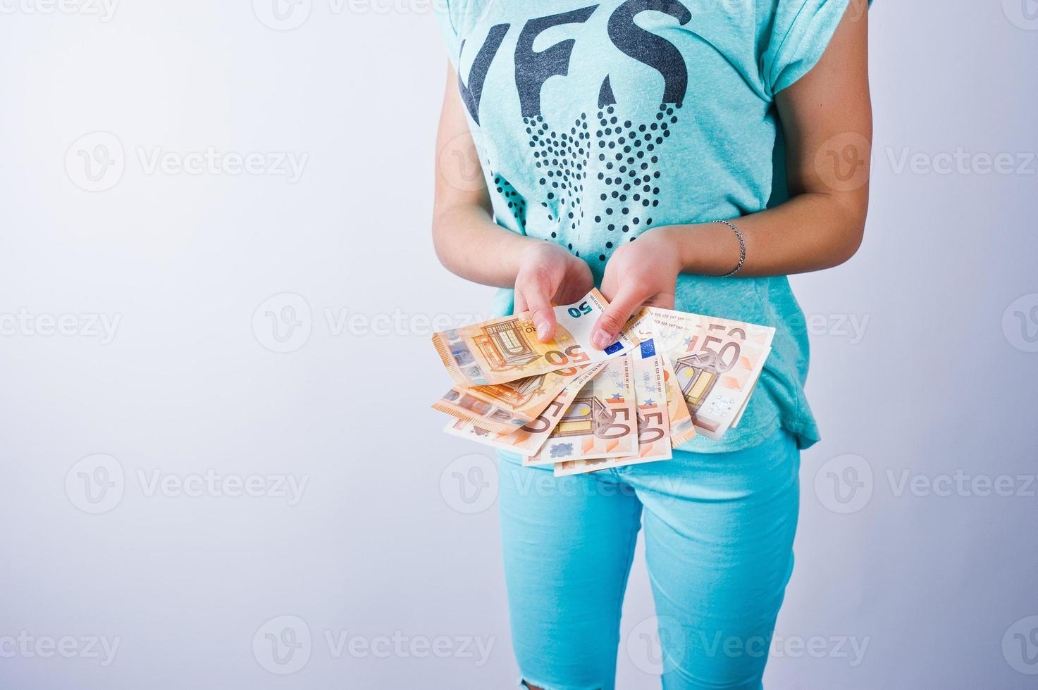 Portrait of an attractive girl in blue or turquoise t-shirt and trousers posing with a lot of money in her hand. photo