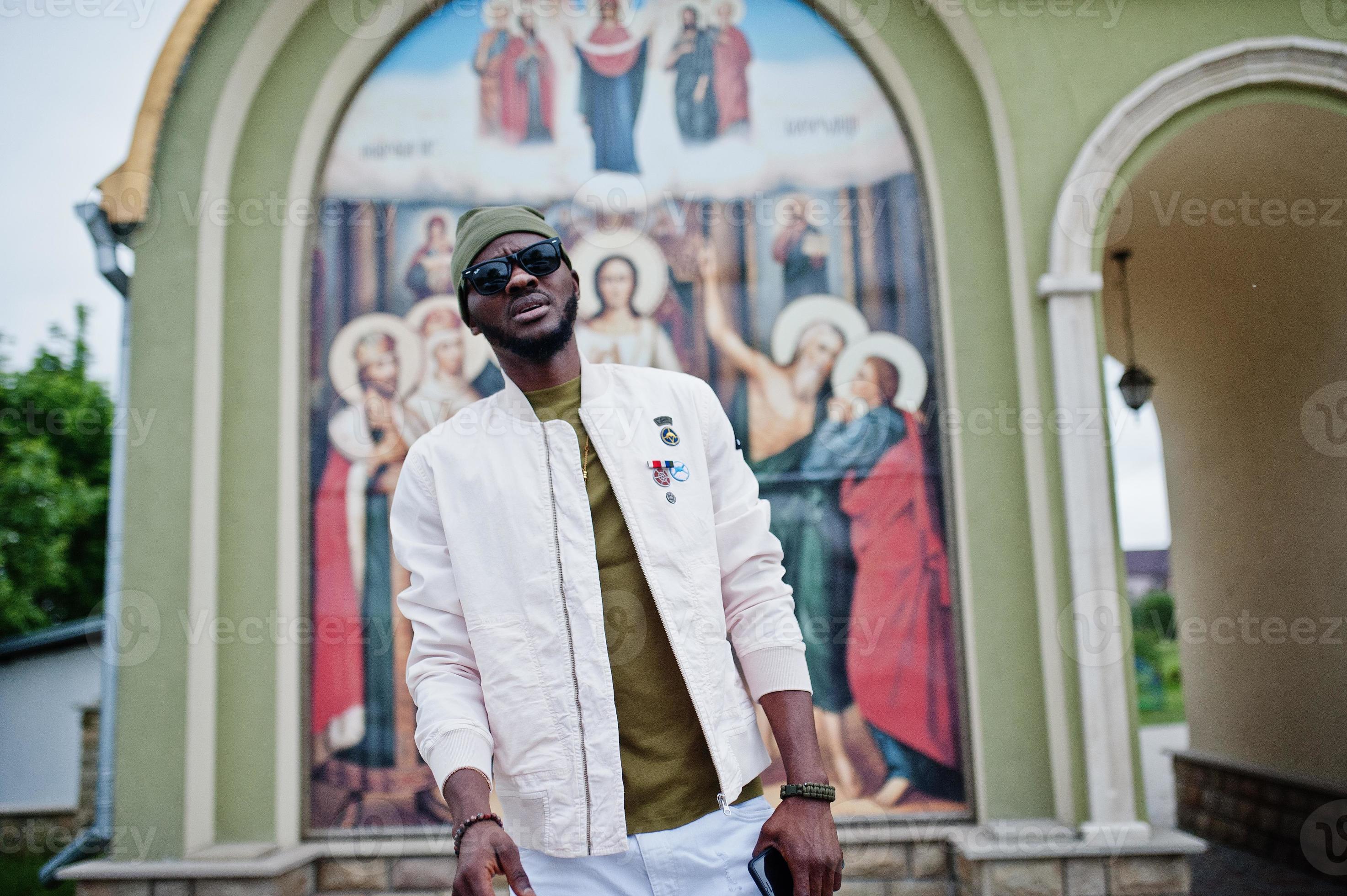 African american man in hat and sunglasses stand against church. Faith