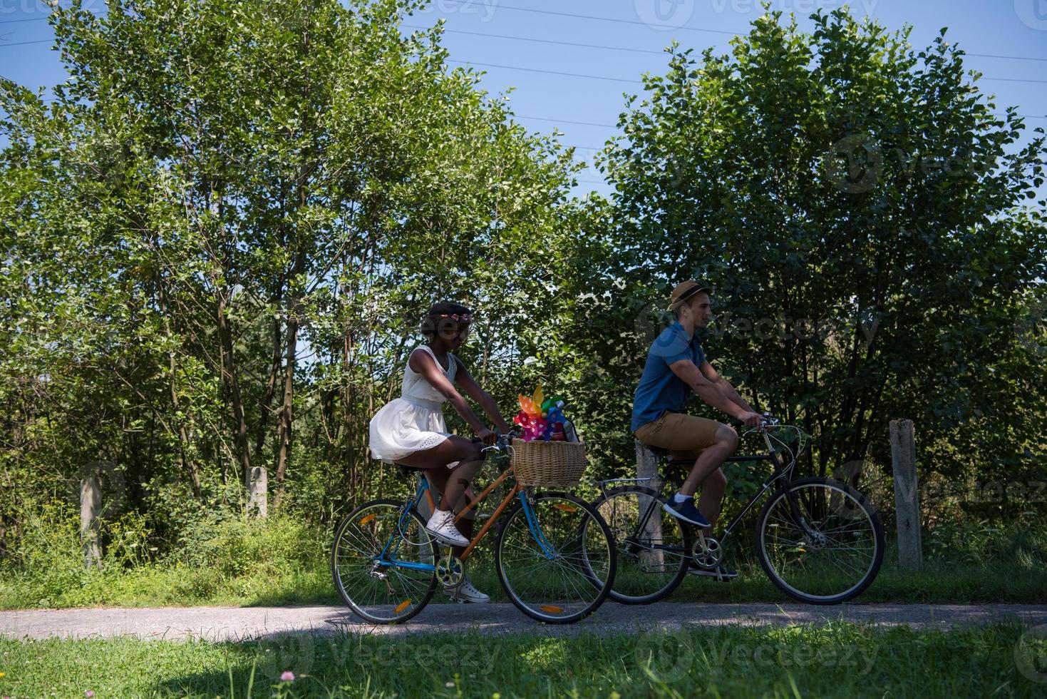 joven pareja multiétnica dando un paseo en bicicleta en la naturaleza foto