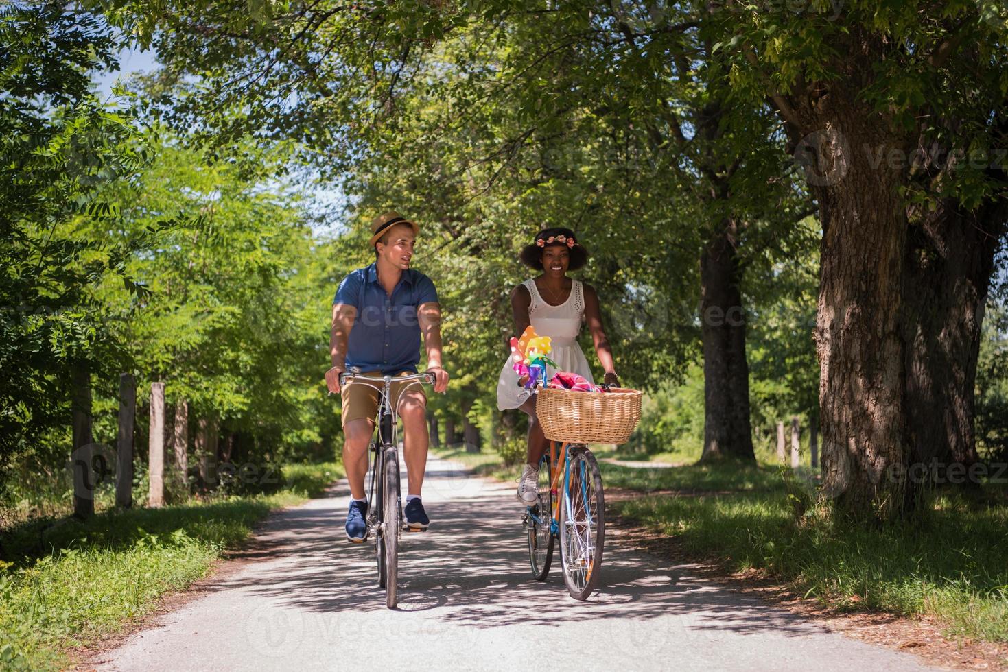 joven pareja multiétnica dando un paseo en bicicleta en la naturaleza foto