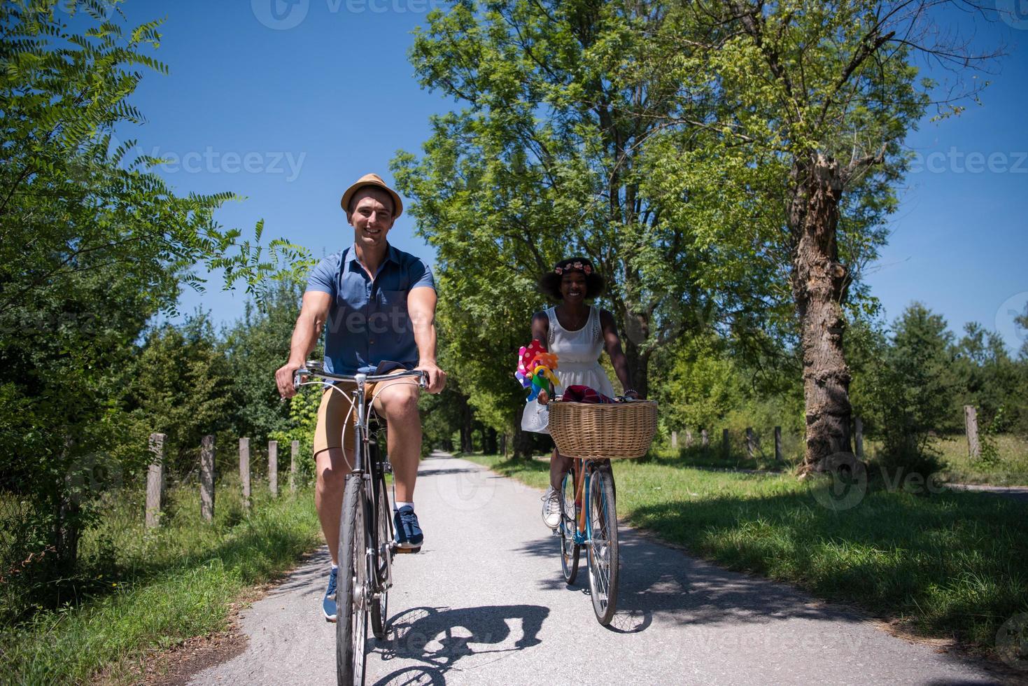 joven pareja multiétnica dando un paseo en bicicleta en la naturaleza foto