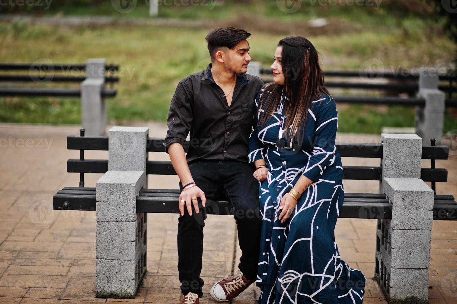 Love story of indian couple posed outdoor, sitting on bench together. photo