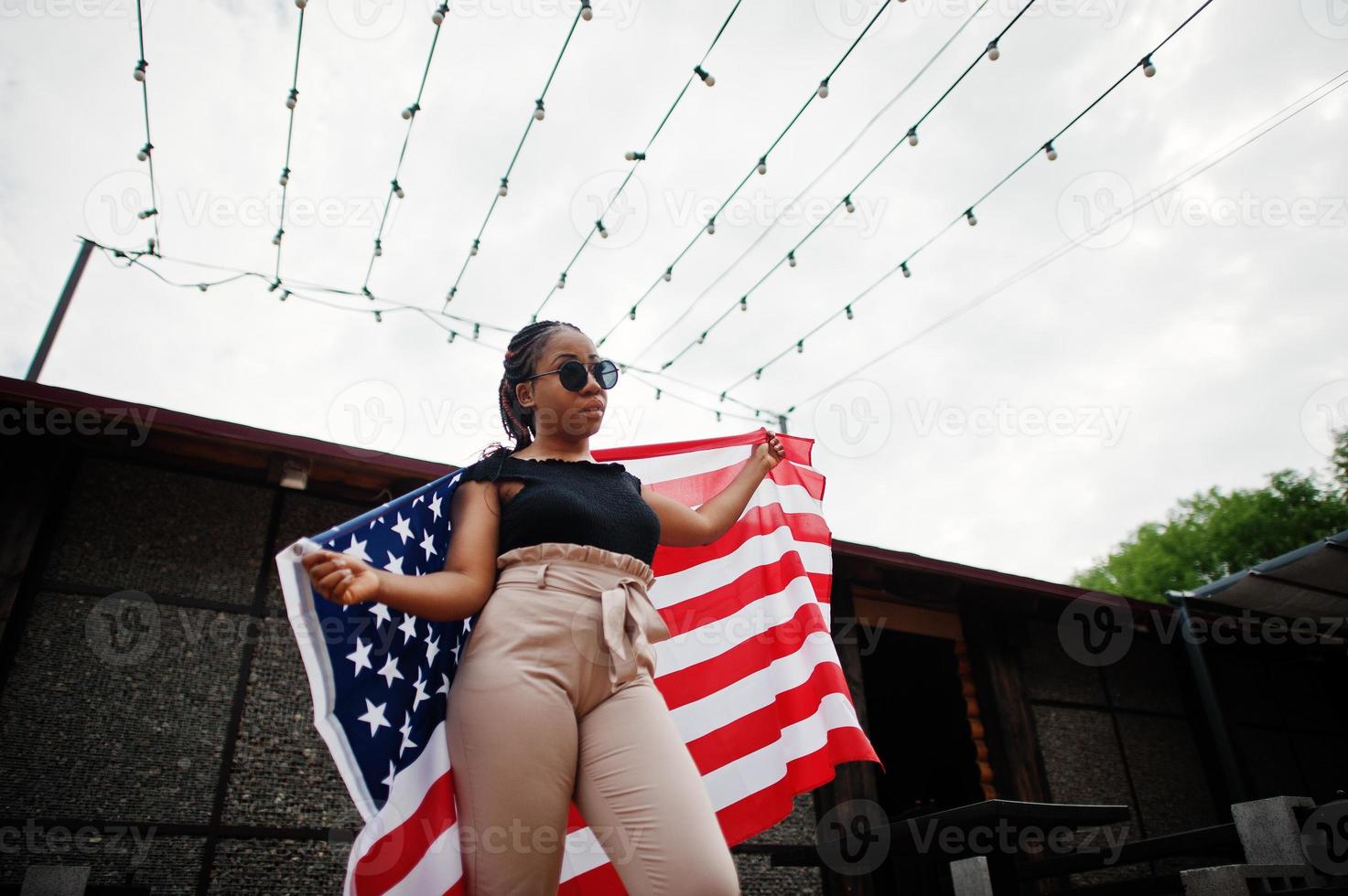 Stylish african american woman in sunglasses posed outdoor with usa flag. photo