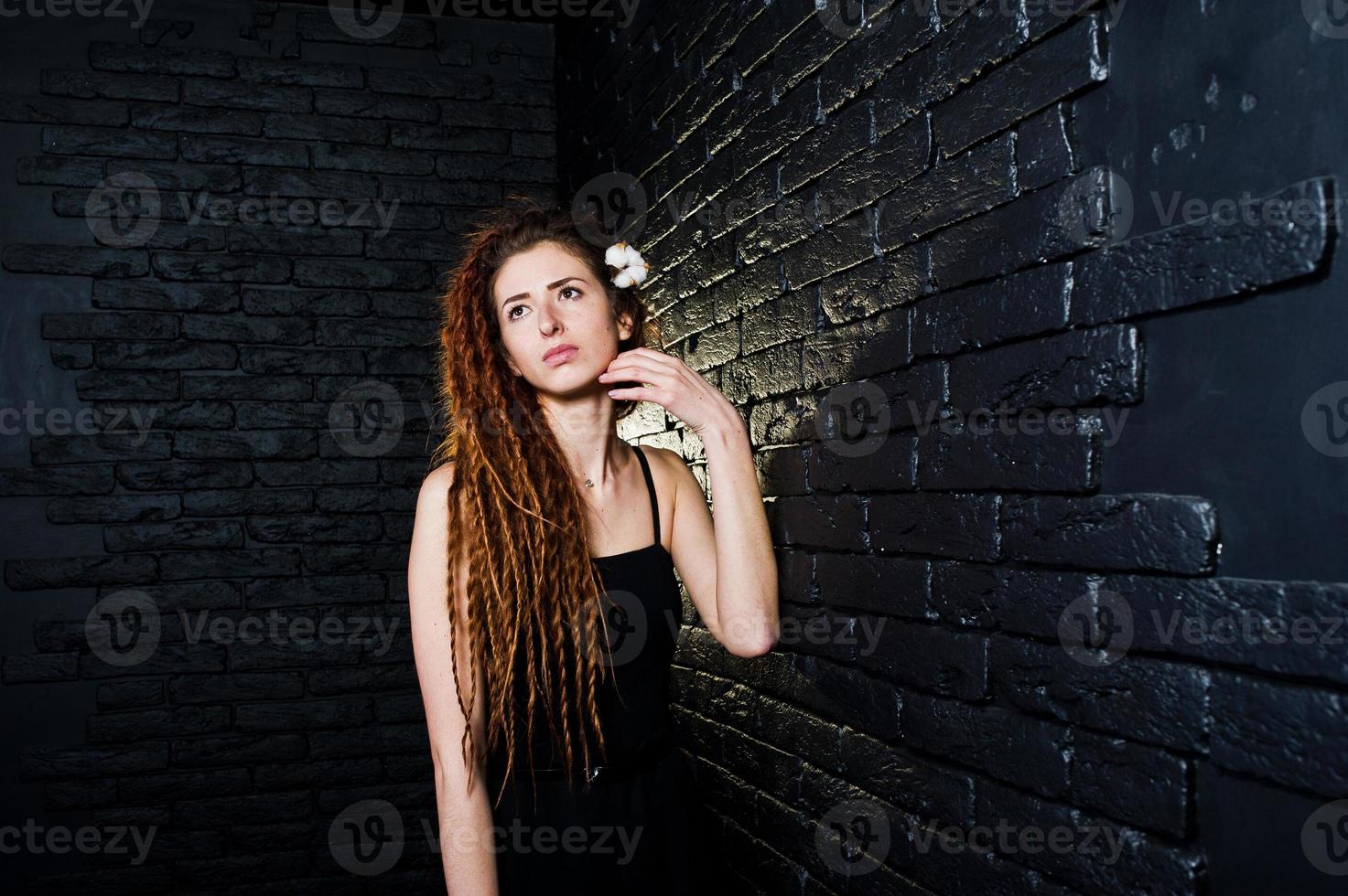 Studio shoot of girl in black with dreads on brick background. photo