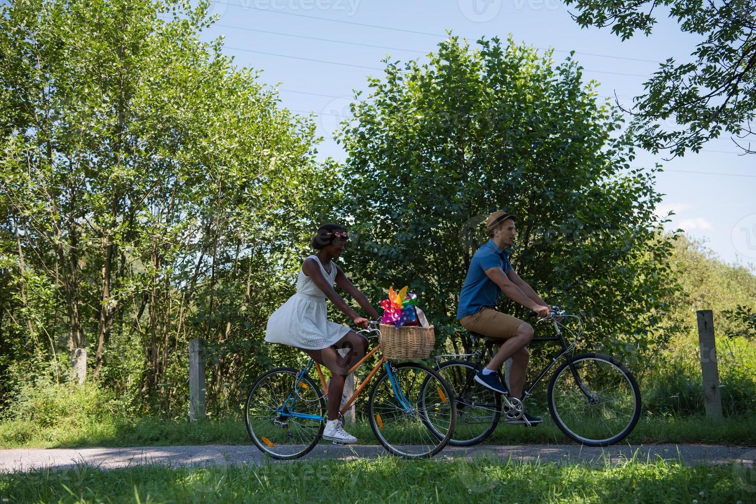 joven pareja multiétnica dando un paseo en bicicleta en la naturaleza foto