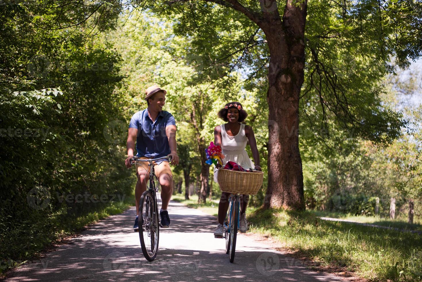 joven pareja multiétnica dando un paseo en bicicleta en la naturaleza foto