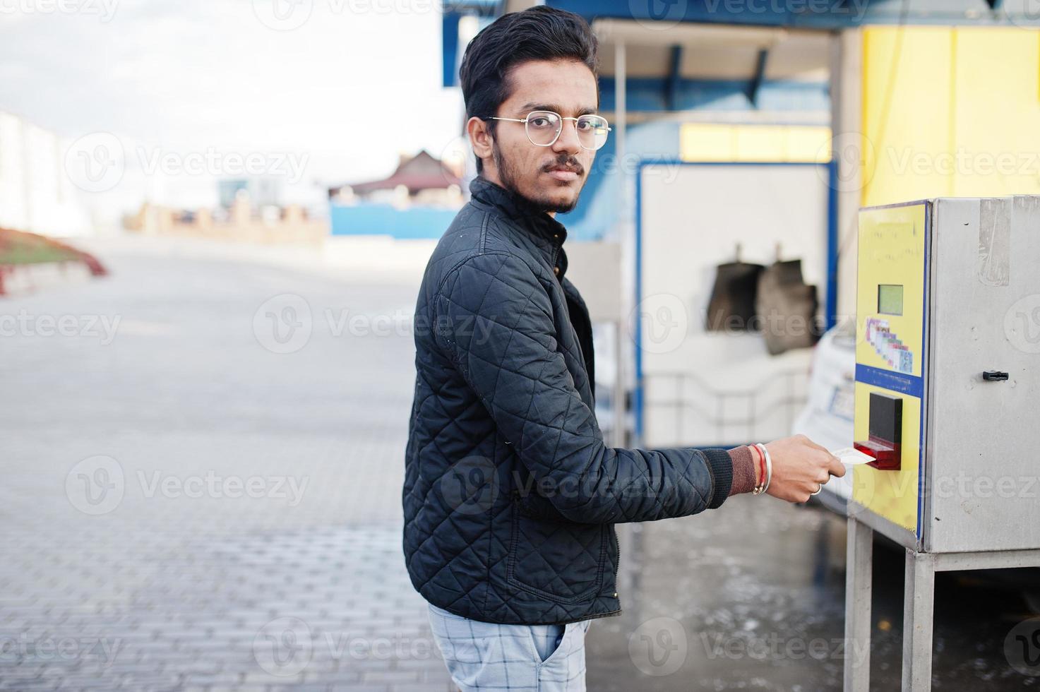 hombre del sur de asia o hombre indio lavando su transporte blanco en el lavado de autos. está poniendo dinero en el cajero automático. foto