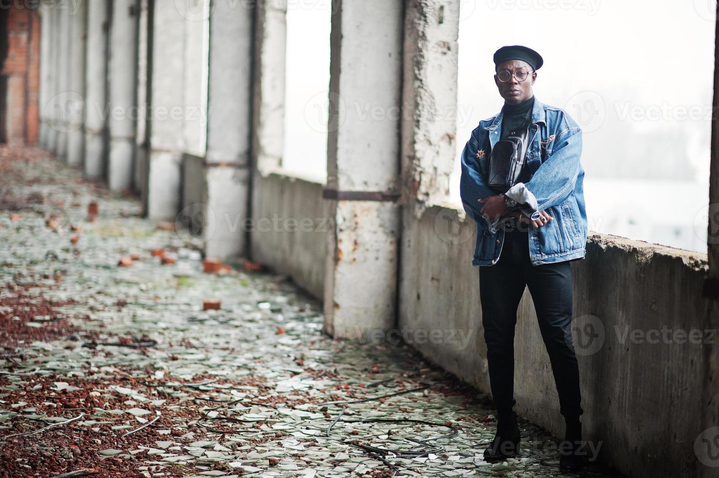 African american man in jeans jacket, beret and eyeglasses at abandoned brick factory. photo