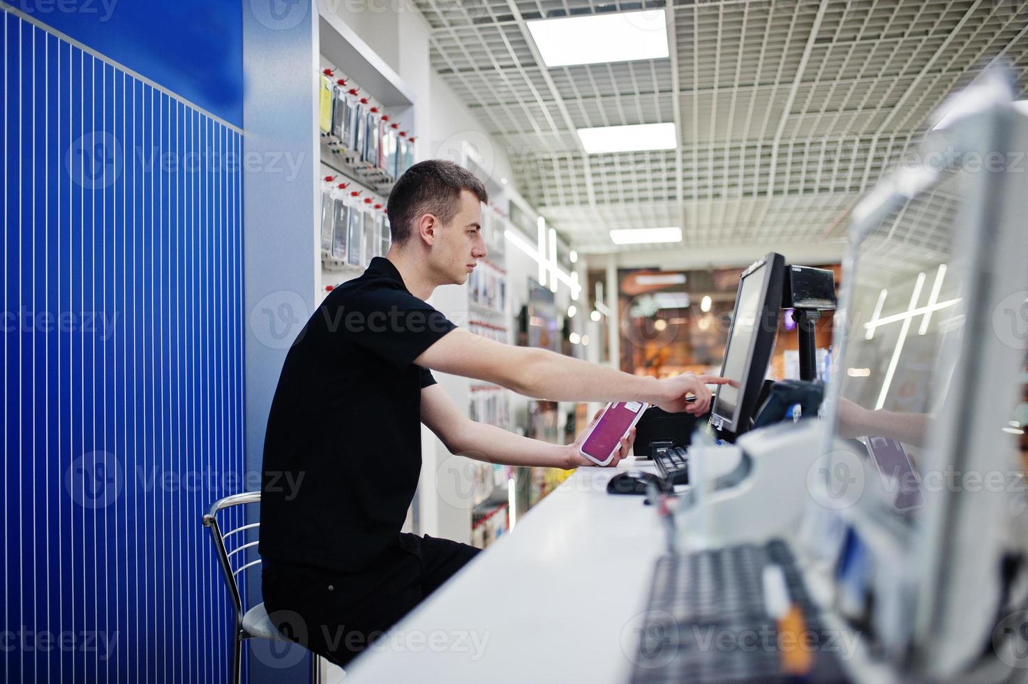 vendedor hombre consultor profesional de telefonía móvil en tienda de tecnología o tienda trabaja en el cajero. foto