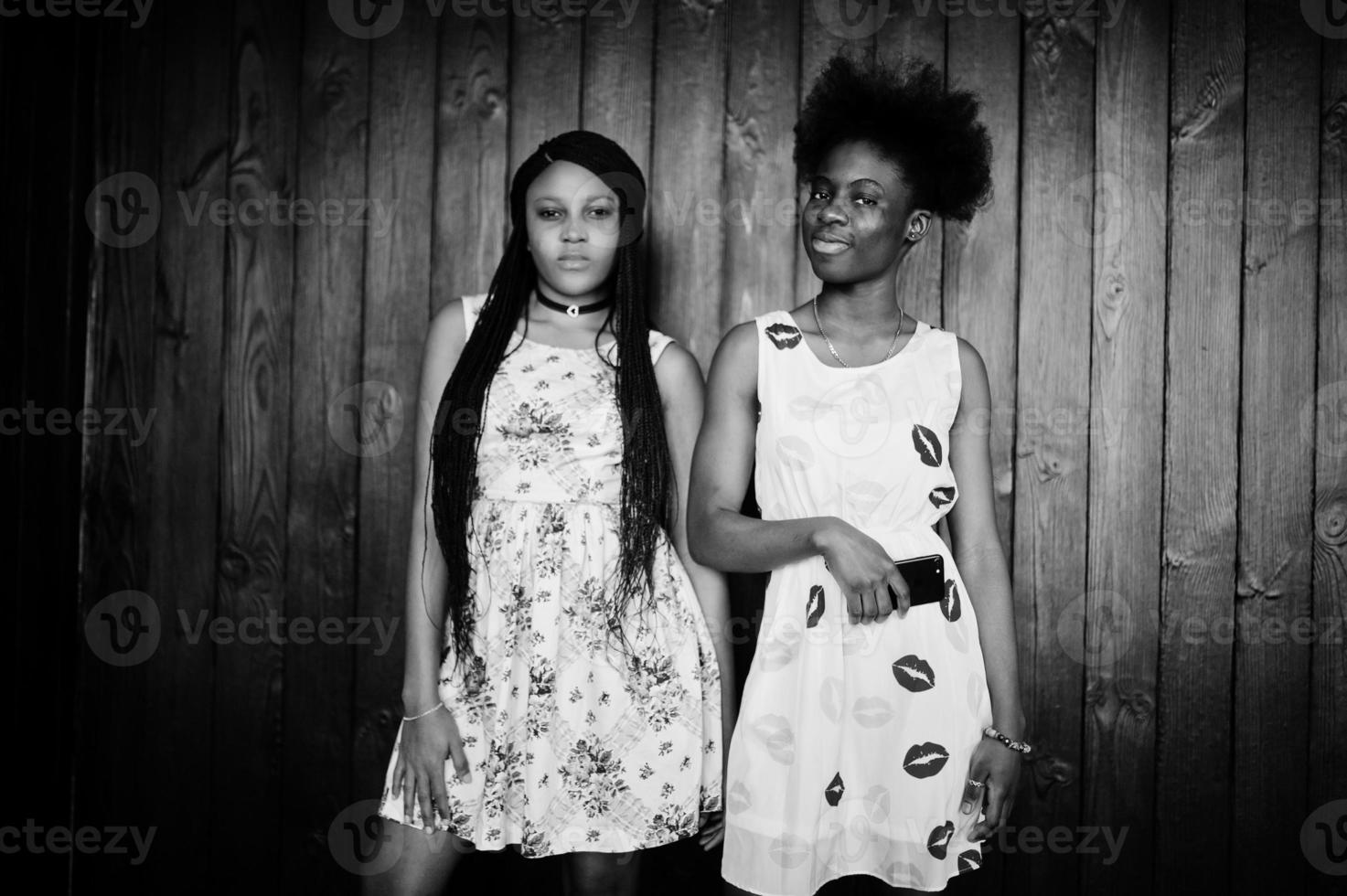 dos novias africanas negras con vestidos de verano posaron sobre un fondo de madera oscura. foto