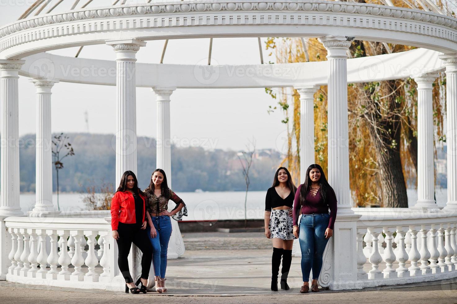 Group of four happy and pretty latino girls from Ecuador posed at street against ancient arch. photo