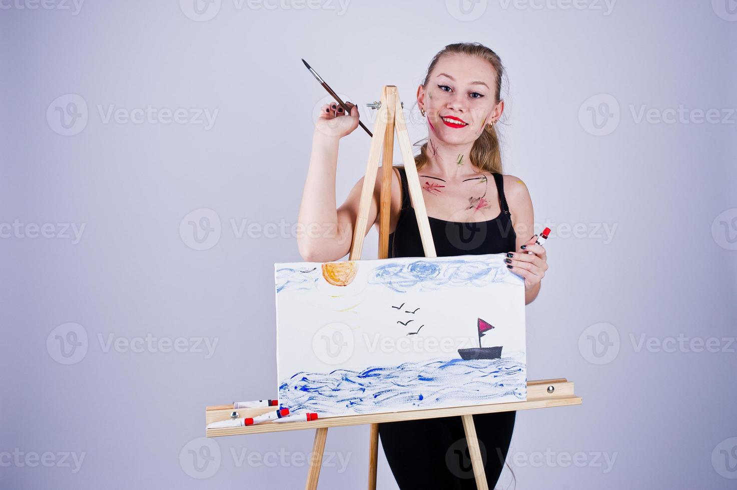 Beautiful woman artist painter with brushes and oil canvas posing in studio isolated on white. photo