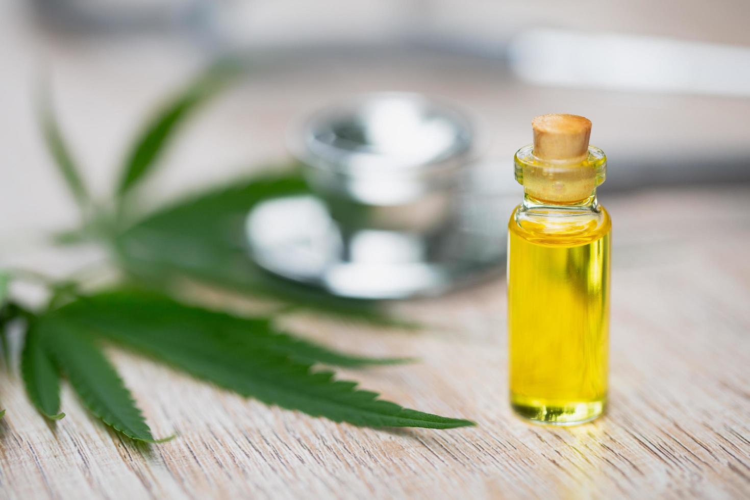 CBD Hemp oil, marijuana plant and cannabis oil on wooden table, medical marijuana oil concept photo