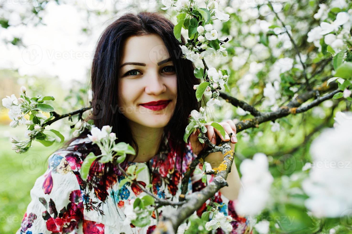 Spring portrait of brunette girl at green blossom garden. photo