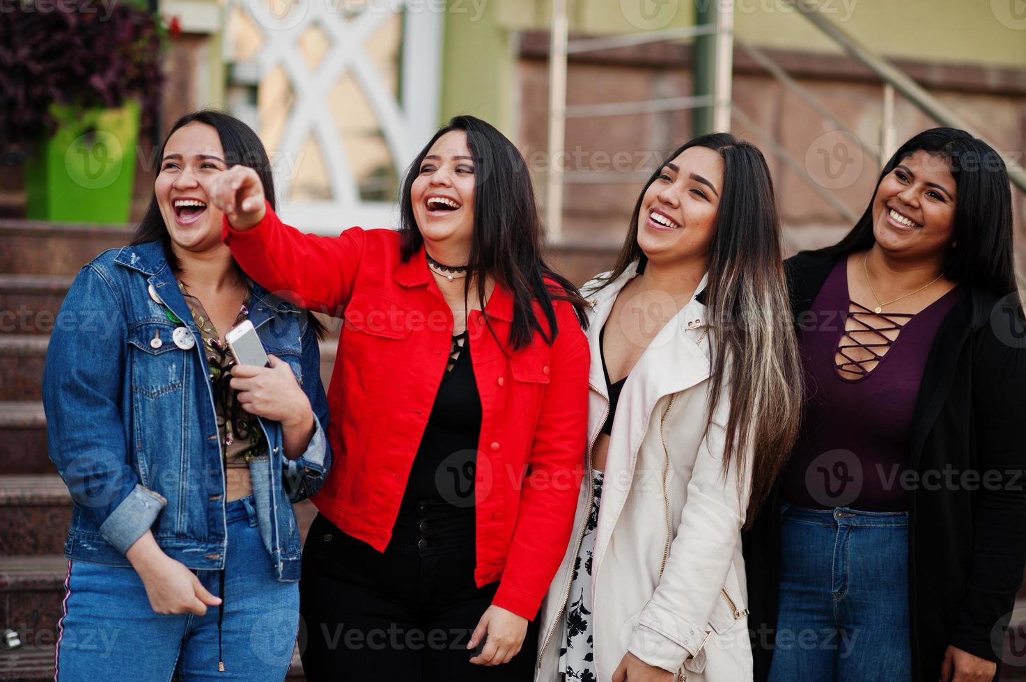 Group of four happy and pretty latino girls from Ecuador posed at street. photo