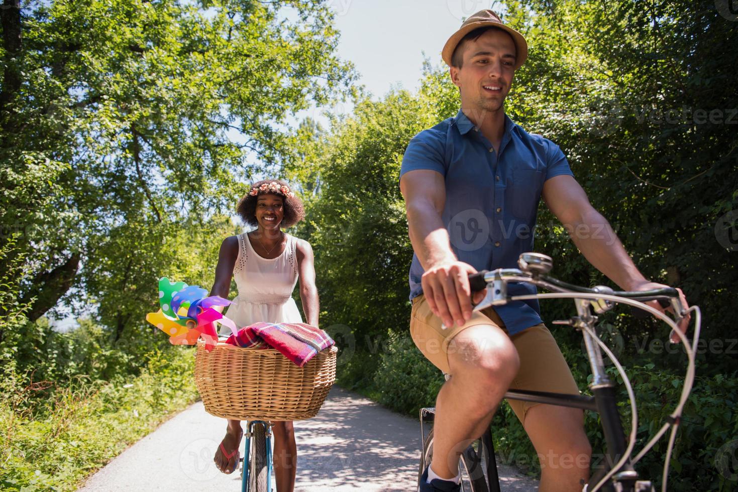 joven pareja multiétnica dando un paseo en bicicleta en la naturaleza foto