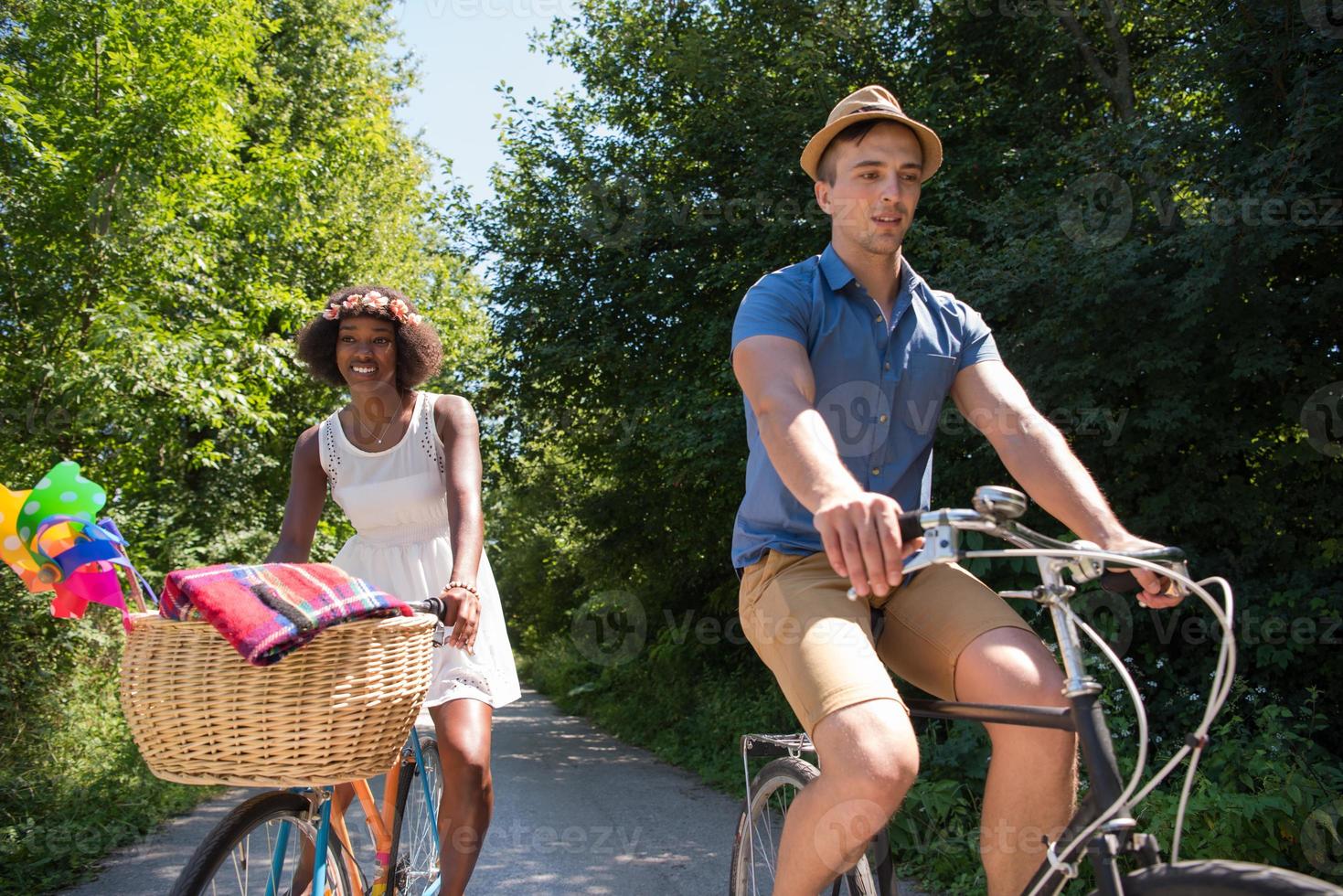 joven pareja multiétnica dando un paseo en bicicleta en la naturaleza foto