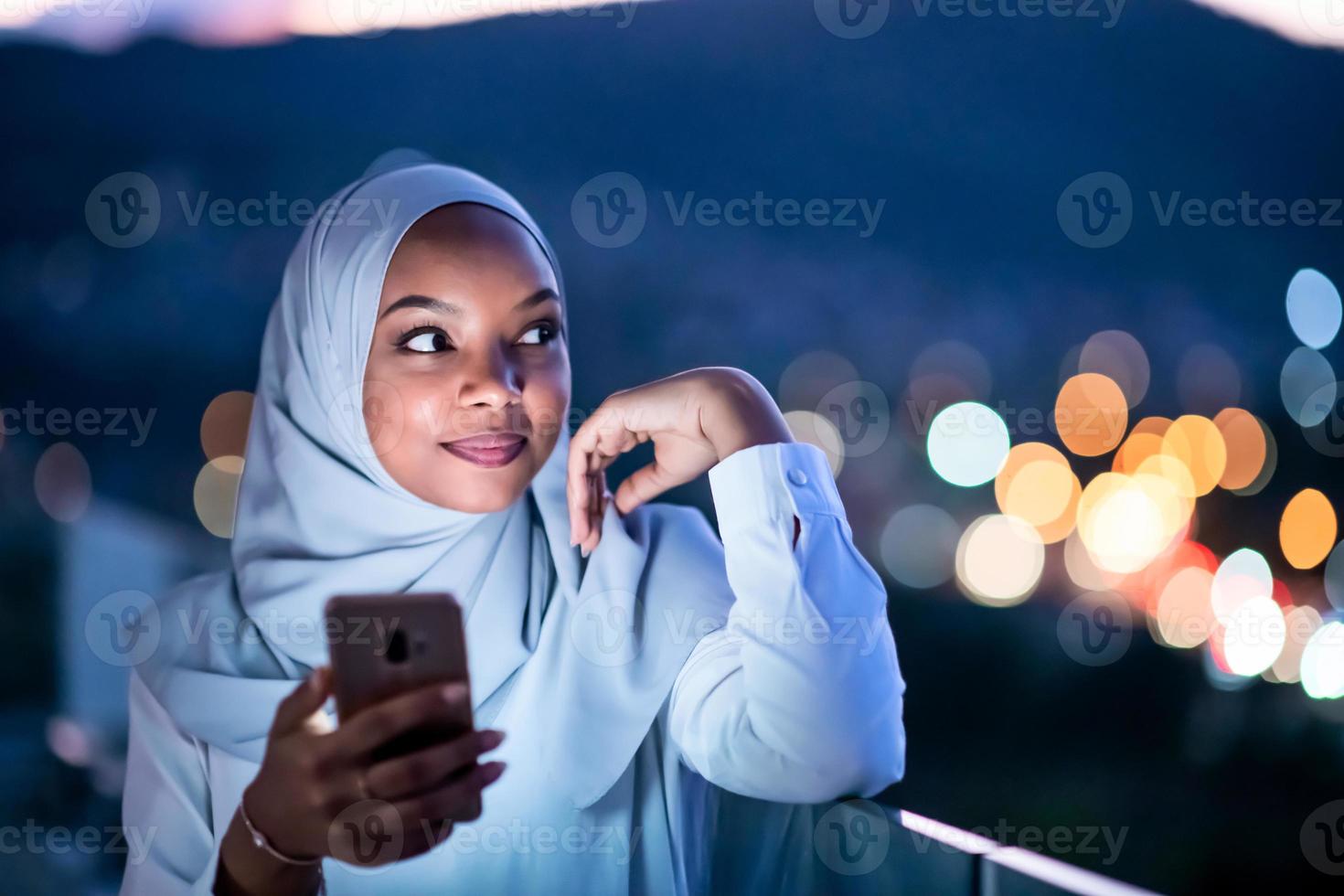 joven musulmana en la calle por la noche usando el teléfono foto