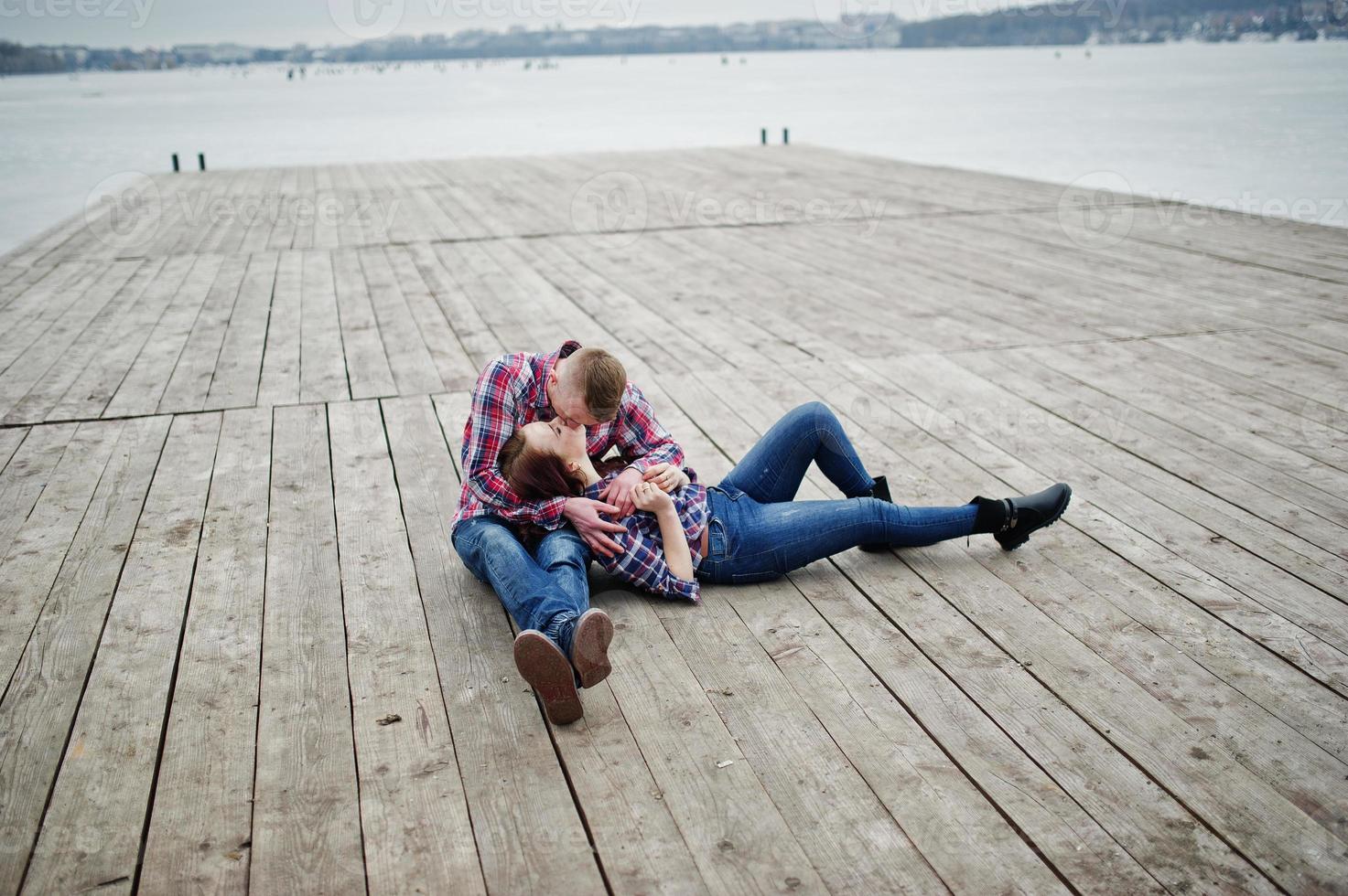 elegante pareja vestida con camisa a cuadros enamorada sentada en el muelle. foto