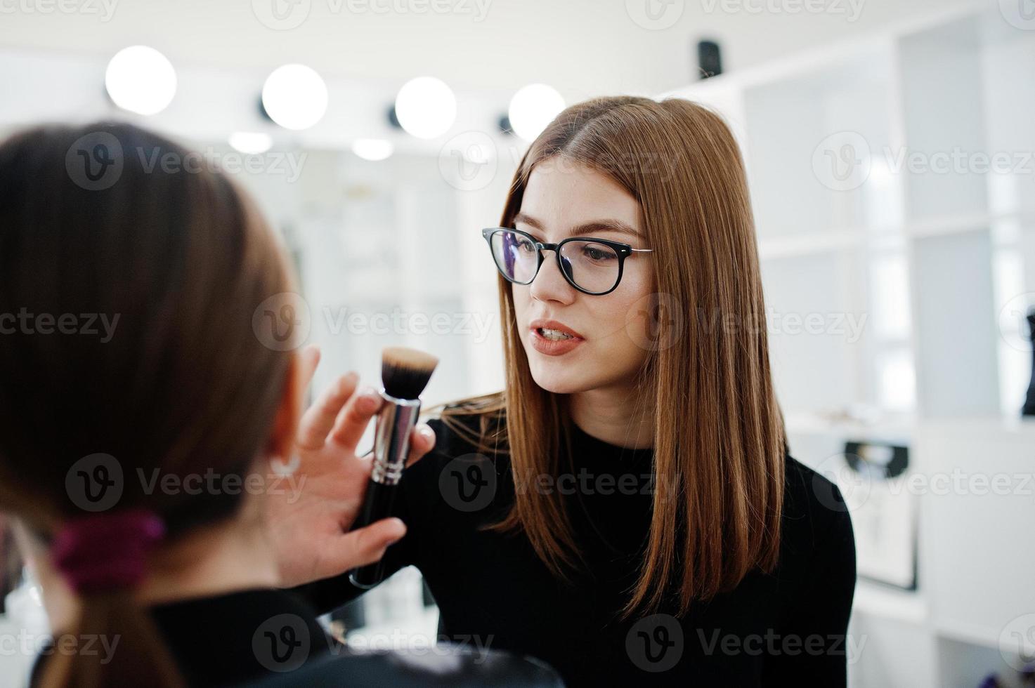 Make up artist work in her beauty visage studio salon. Woman applying by professional make up master. Beauty club concept. photo