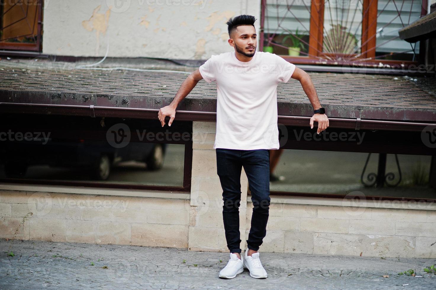 Stylish indian beard man at pink t-shirt. India model posed outdoor at streets of city. photo
