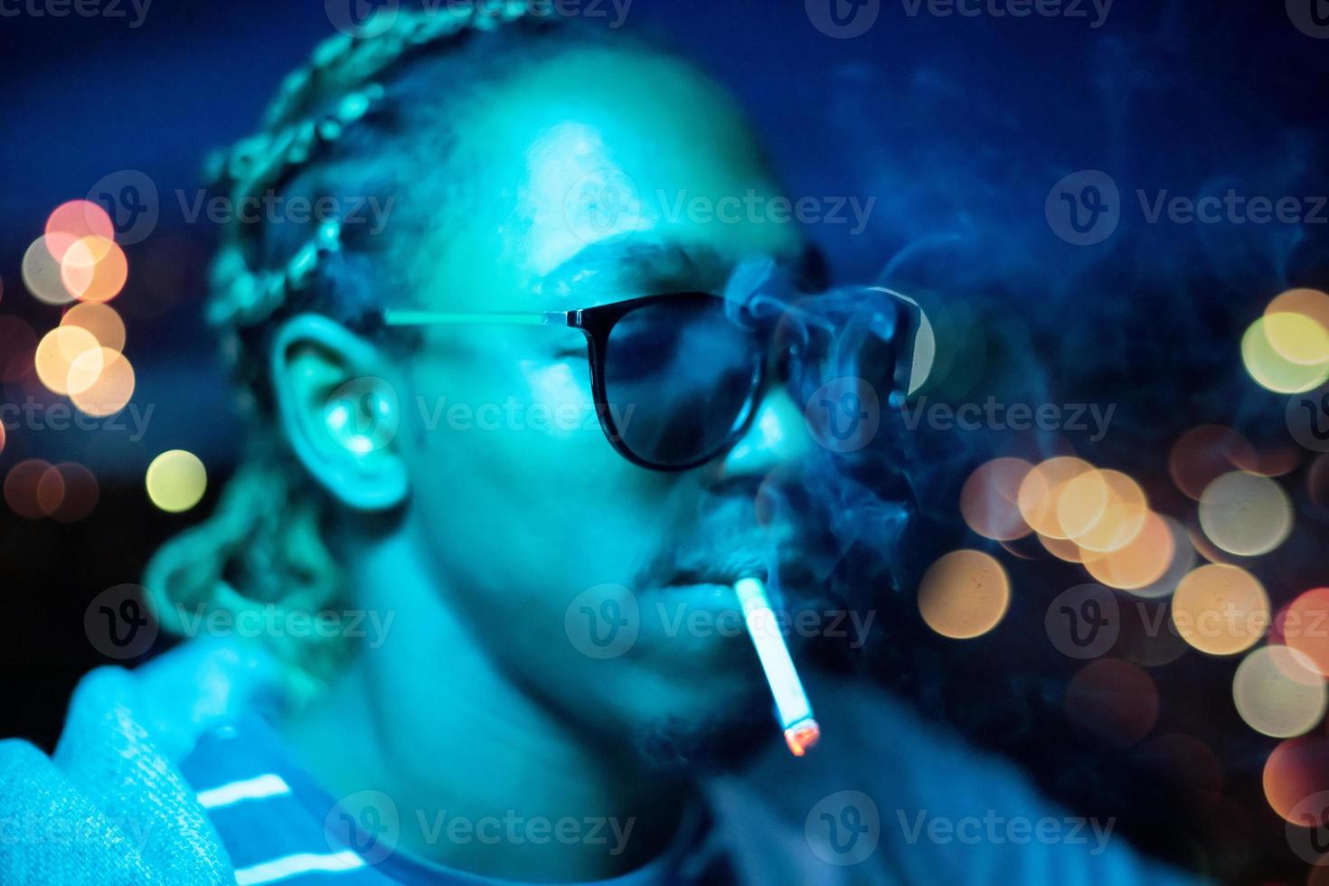 african american man smoking cigarette  at night photo
