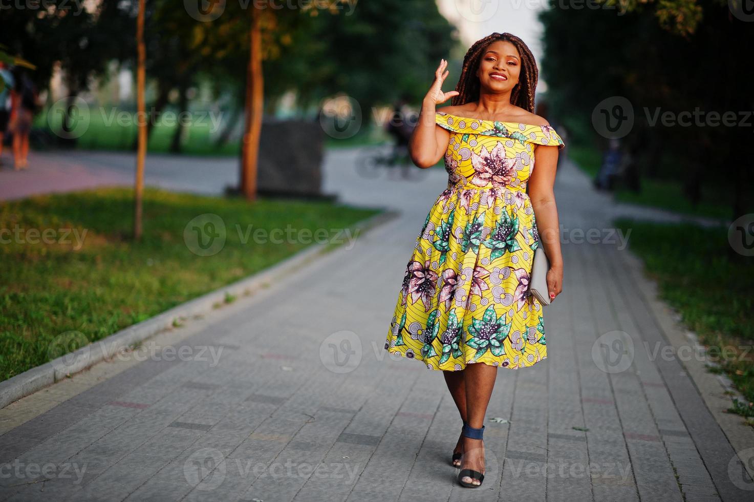 Cute small height african american girl with dreadlocks, wear at coloured yellow dress, posed at sunset. photo