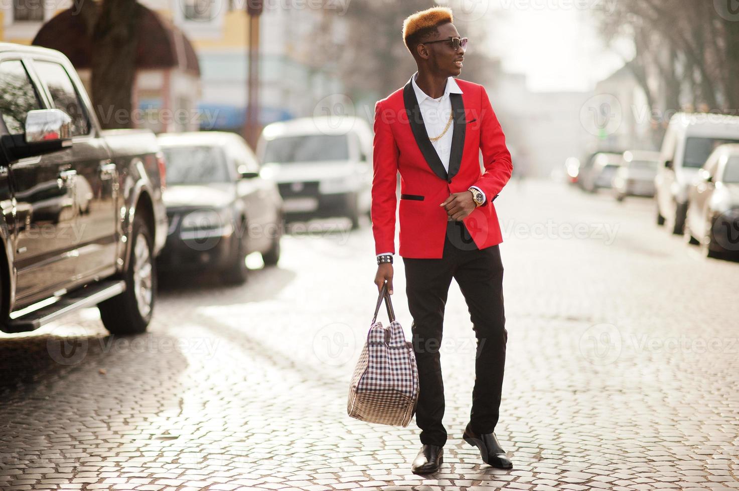 Fashion african american man model at red suit, with highlights hair and handbag posed at street. photo