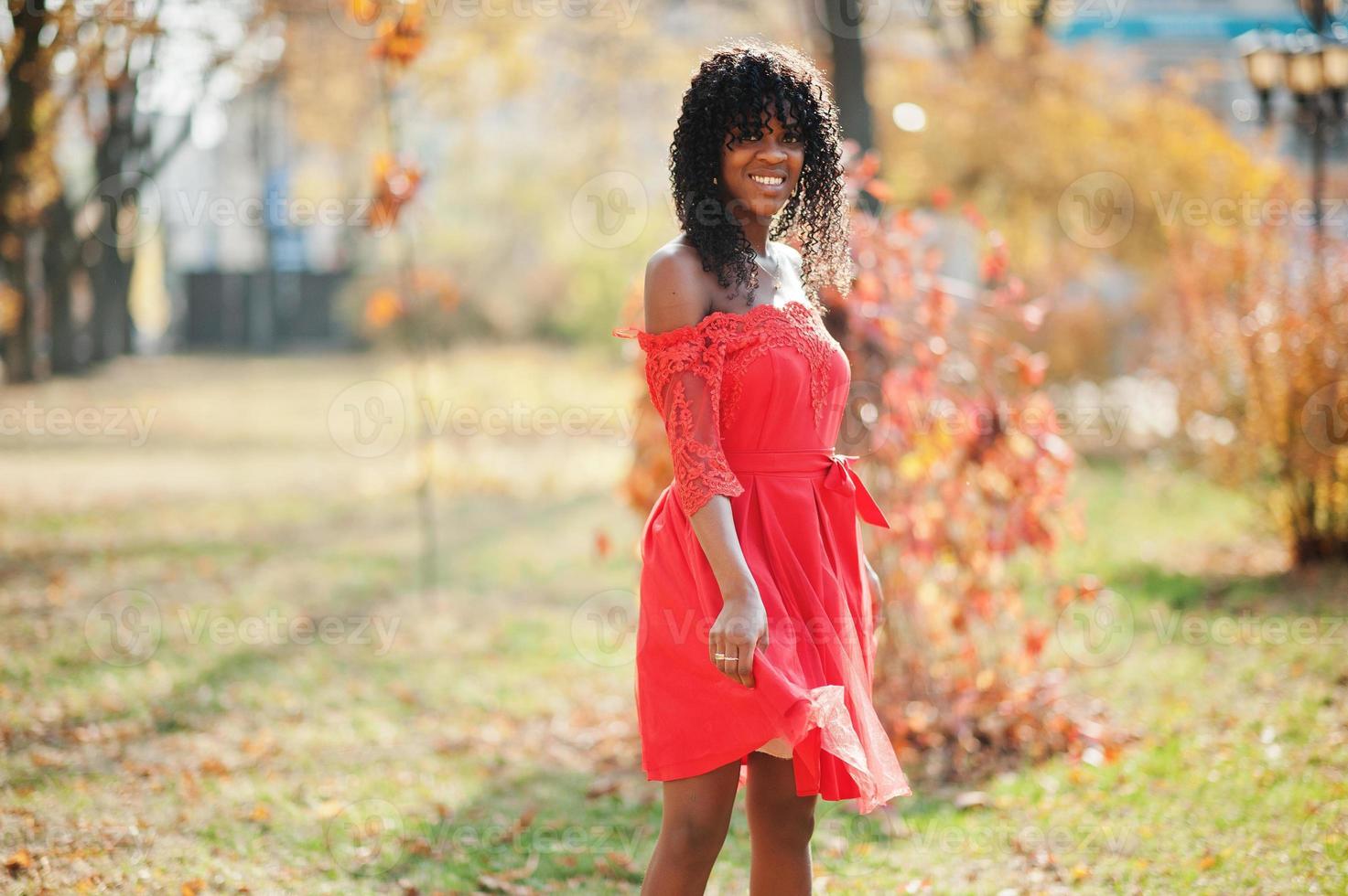 elegante mujer rizada afro francia de moda posó en el día de otoño con vestido rojo. modelo de mujer africana negra. foto