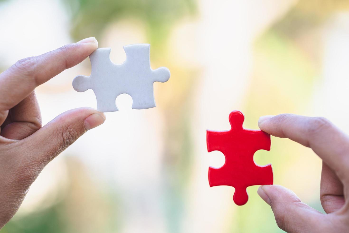 Jigsaw connection between white and red jigsaw puzzles, Jigsaw puzzle in the hand of a businessman,  Business team assembling Jigsaw puzzle. photo