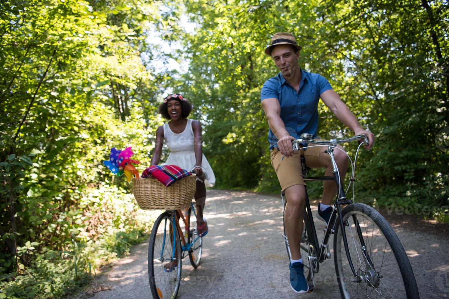 joven pareja multiétnica dando un paseo en bicicleta en la naturaleza foto