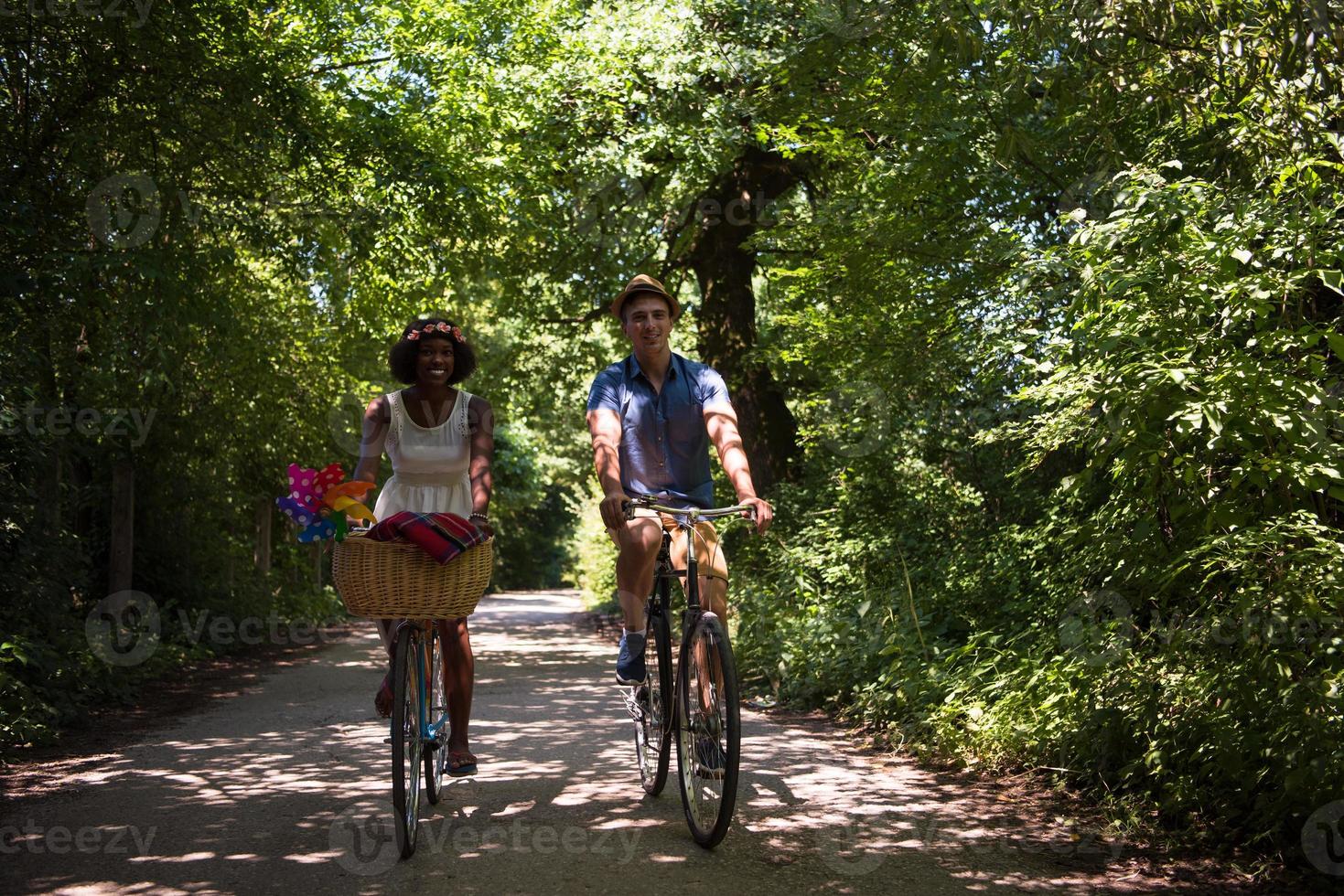 joven pareja multiétnica dando un paseo en bicicleta en la naturaleza foto